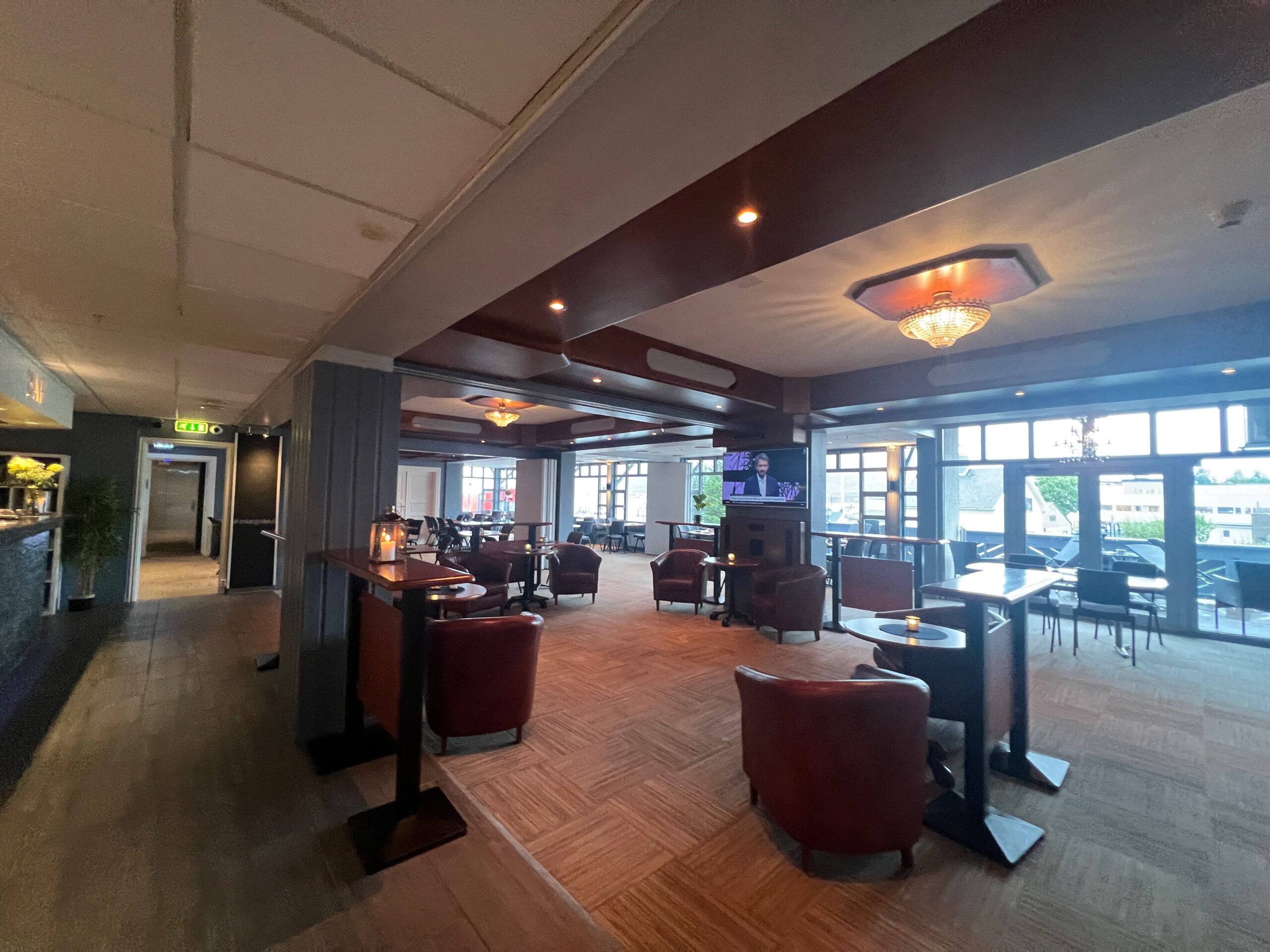 Restaurant and lounge area inside Vestnes Fjordhotel with red armchairs, wooden ceiling beams and large windows in Vestnes Norway