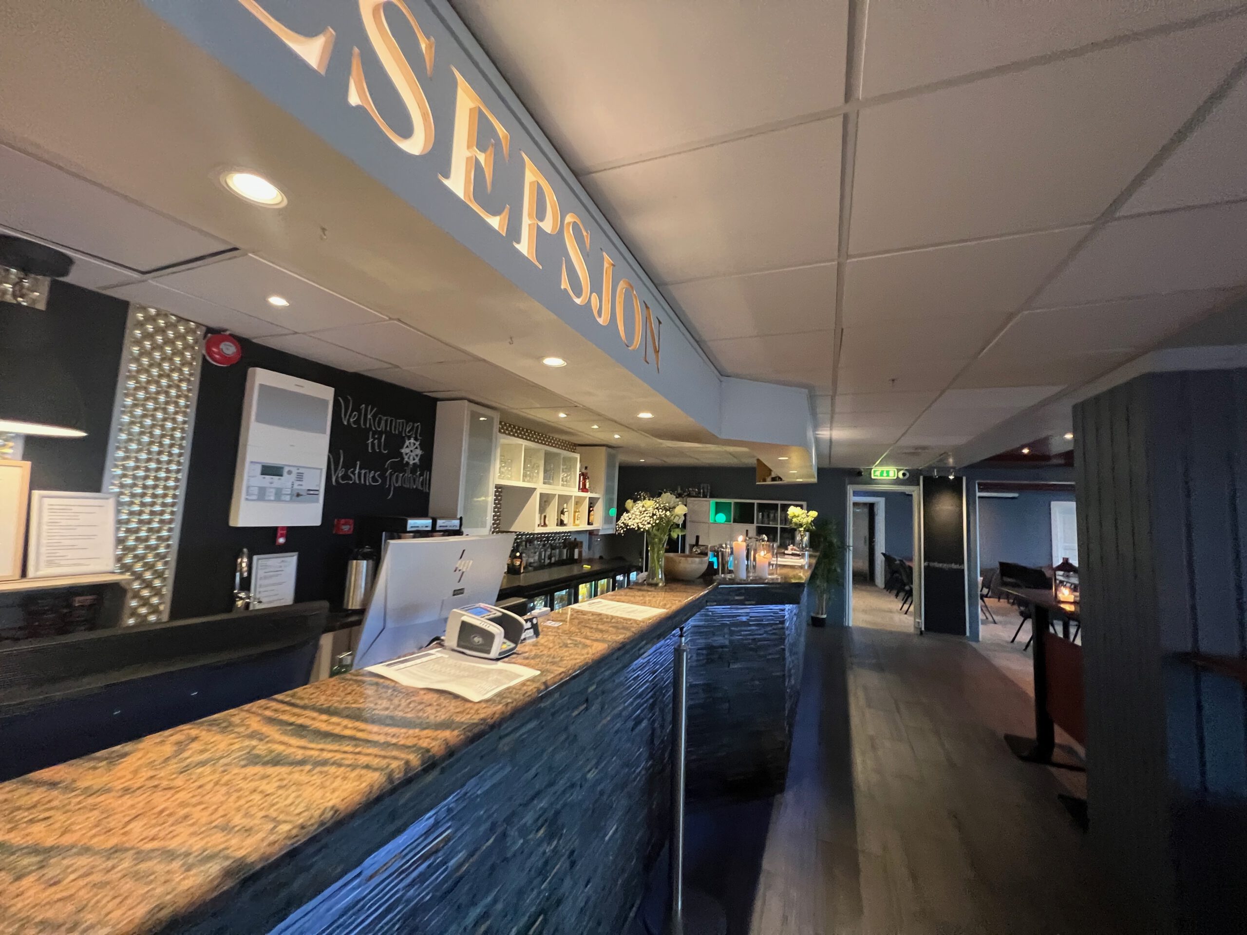 Reception and bar area inside Vestnes Fjordhotel with stone counter, welcome sign, and cozy Norwegian interior in Vestnes Norway
