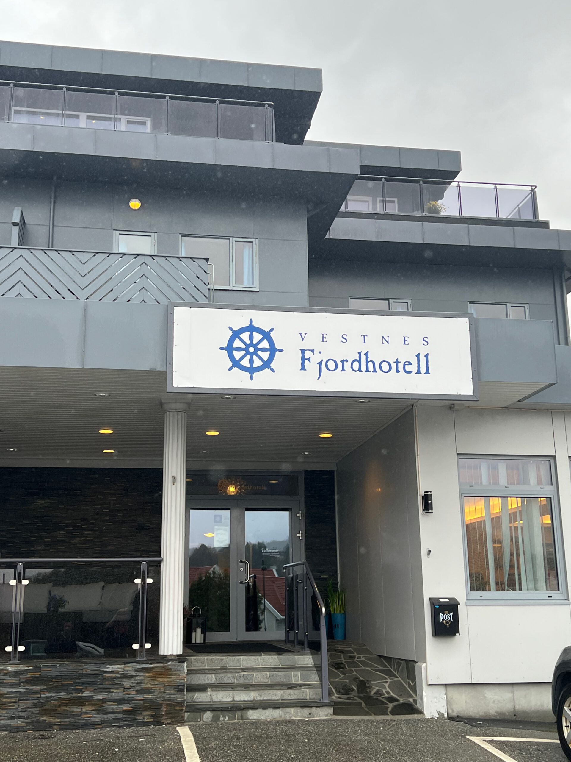 Vestnes Fjordhotel entrance in Vestnes Norway with hotel logo sign, modern grey facade, glass doors, and Norwegian coastal architecture