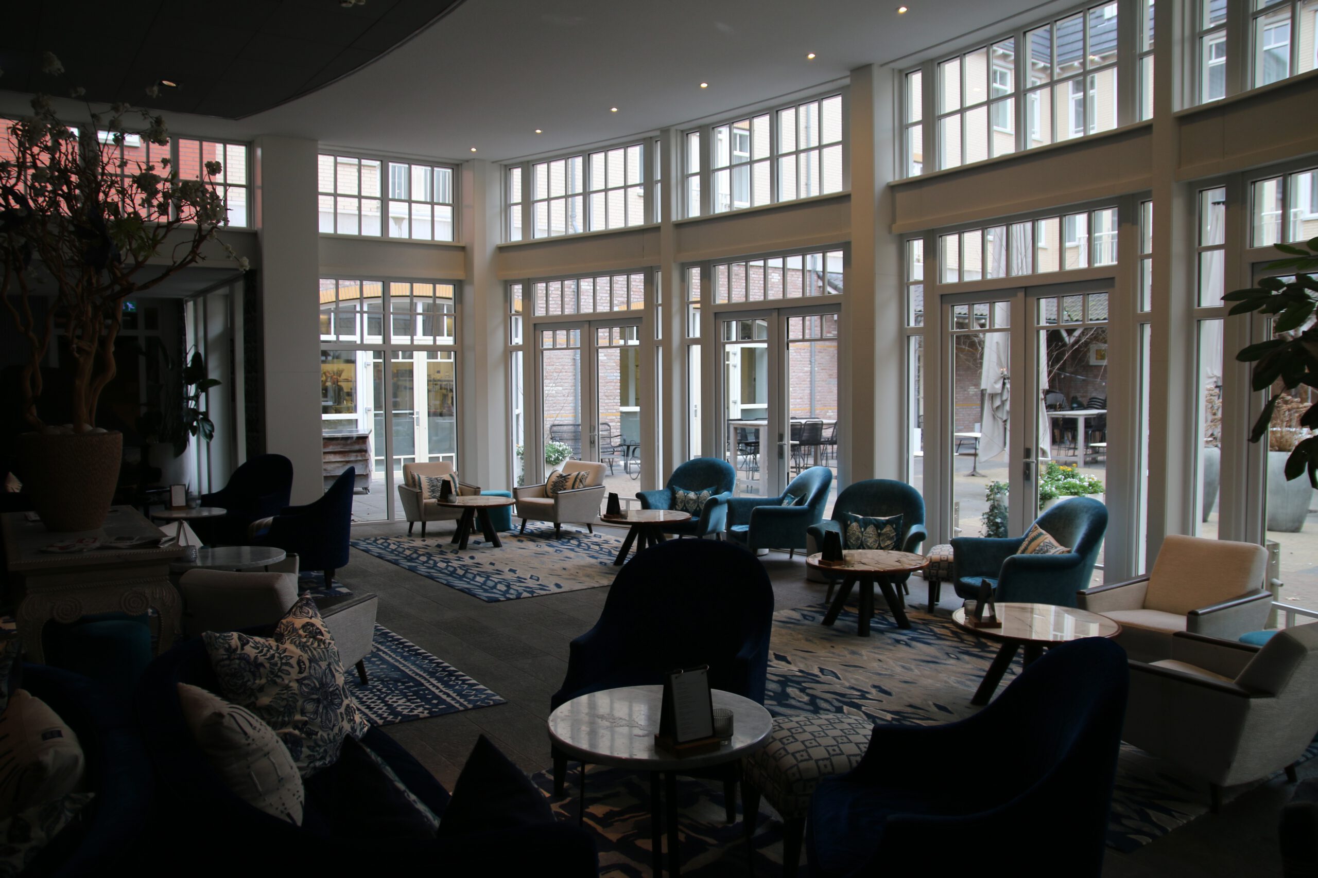 Grand Hotel Ter Duin review stylish lobby lounge in Burgh Haamstede with blue velvet chairs, marble tables, large windows, and bright open seating area