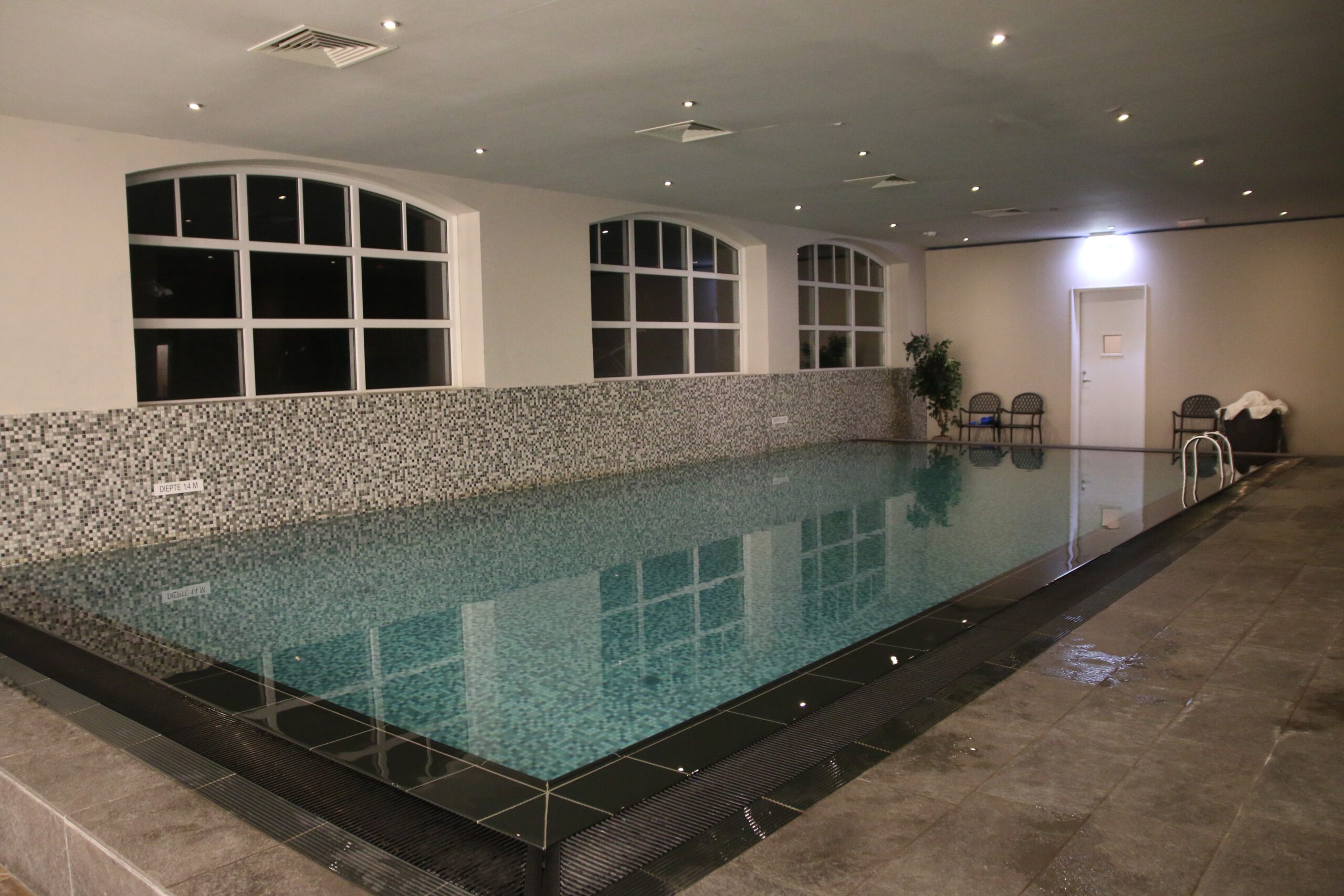 Grand Hotel Ter Duin spa review – wide view of the indoor swimming pool with tiled floor, large windows and relaxing atmosphere in the spa of Grand Hotel Ter Duin.
