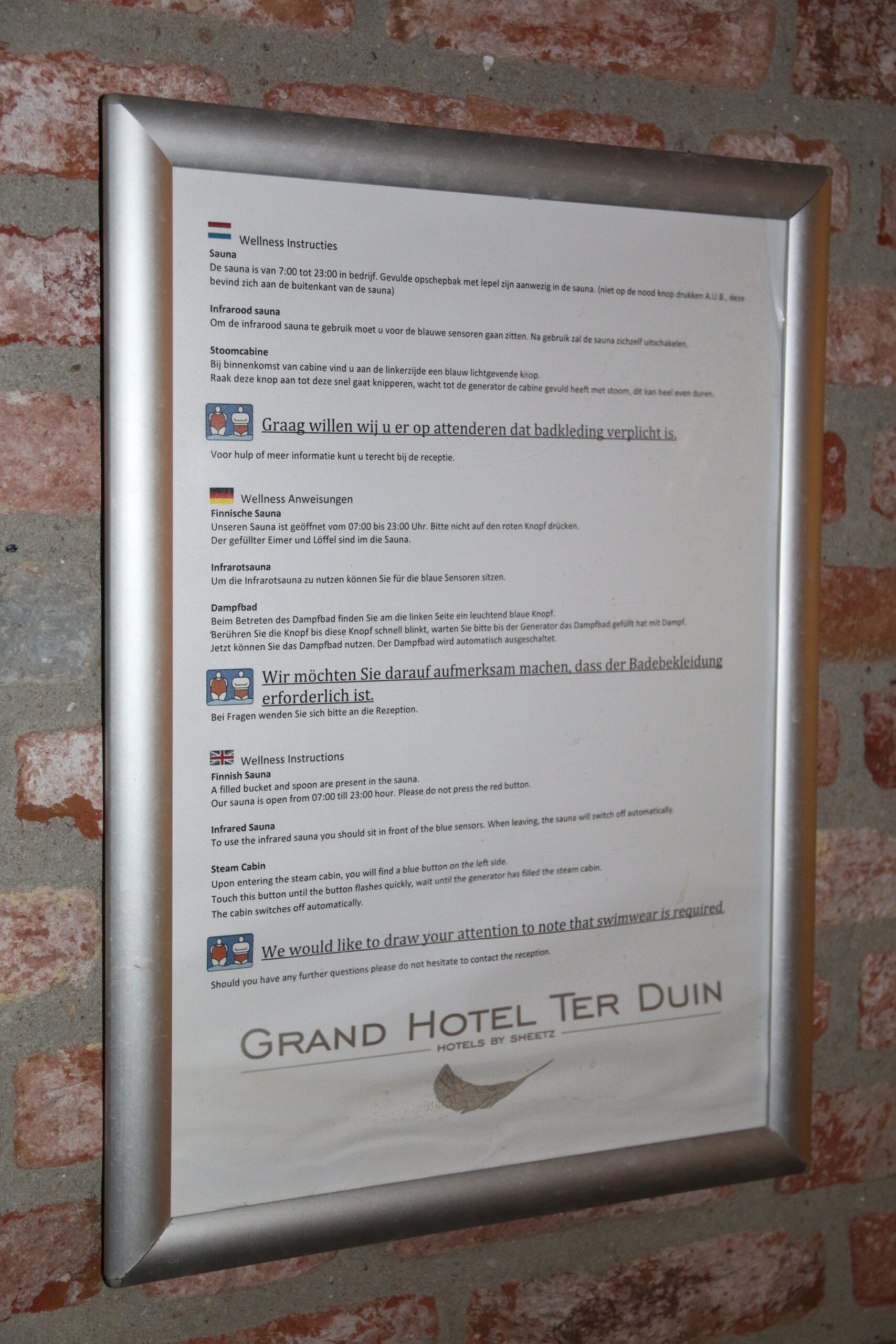 Grand Hotel Ter Duin spa review – wellness instructions sign inside the spa area explaining sauna rules, steam cabin use and mandatory swimwear policy at Grand Hotel Ter Duin.