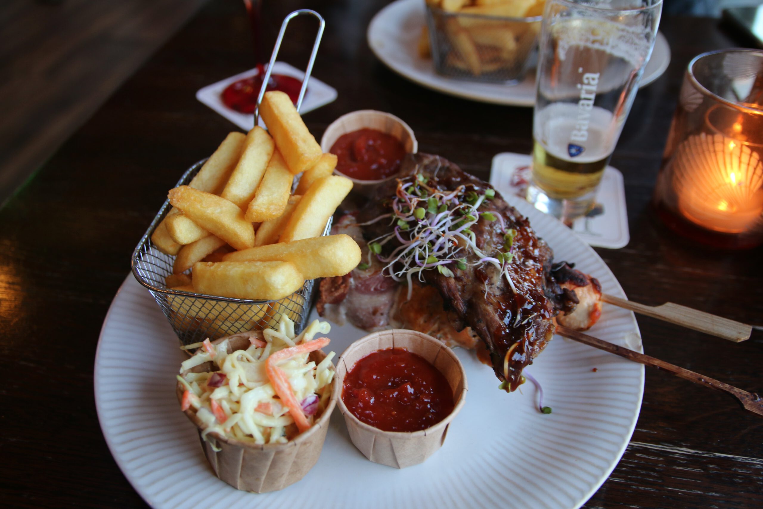 Restaurant Zeebinkie review, Mixed Grill XL at Restaurant Zeebinkie in Burgh Haamstede served with thick cut fries in basket, sparerib with barbecue glaze, grilled meat skewer, coleslaw salad, red barbecue sauce dip and Bavaria Pilsener beer on the table