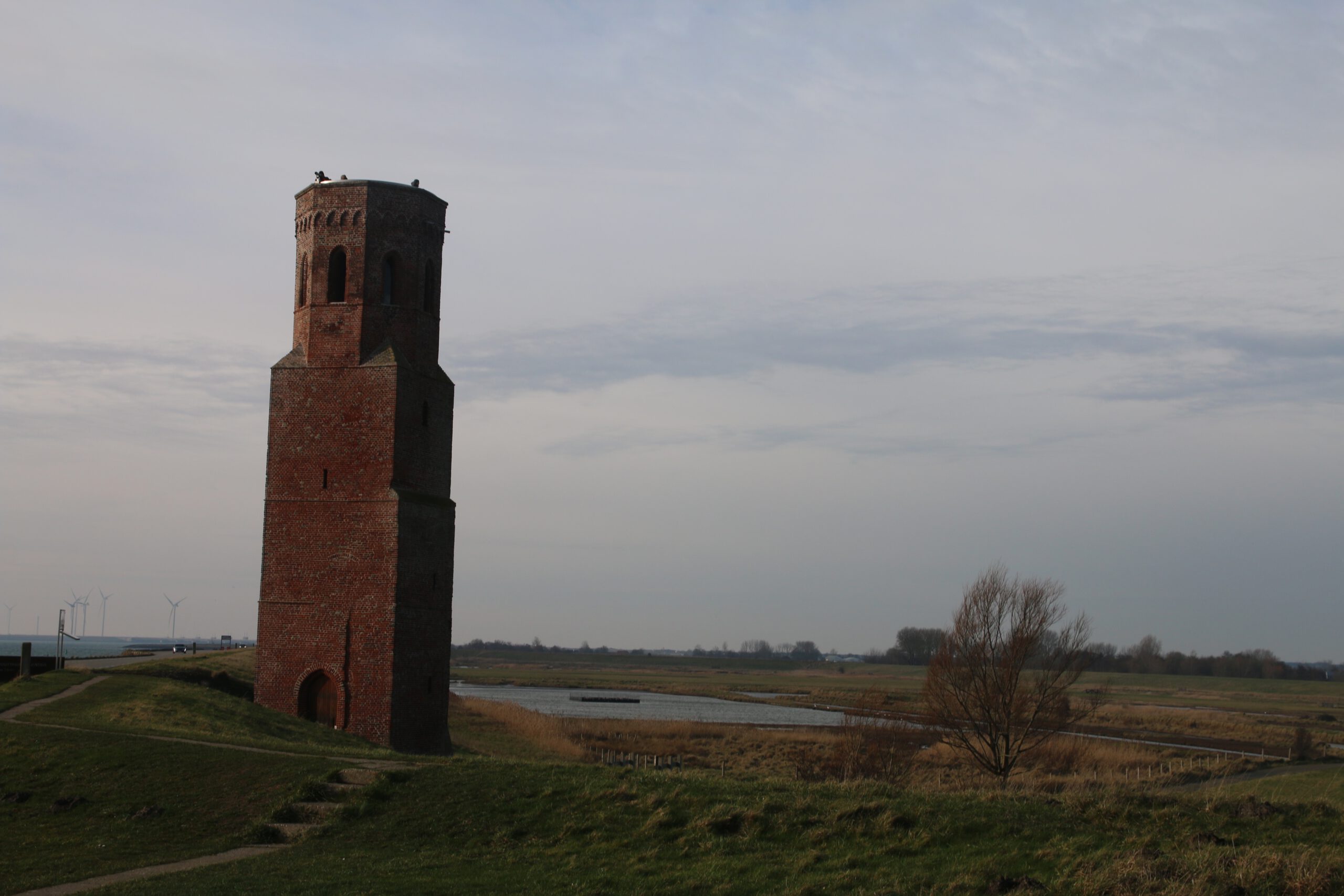 Plompe Toren Koudekerke standing alone along the Oosterschelde dike in Zeeland with open landscape and tidal marshes in the background
