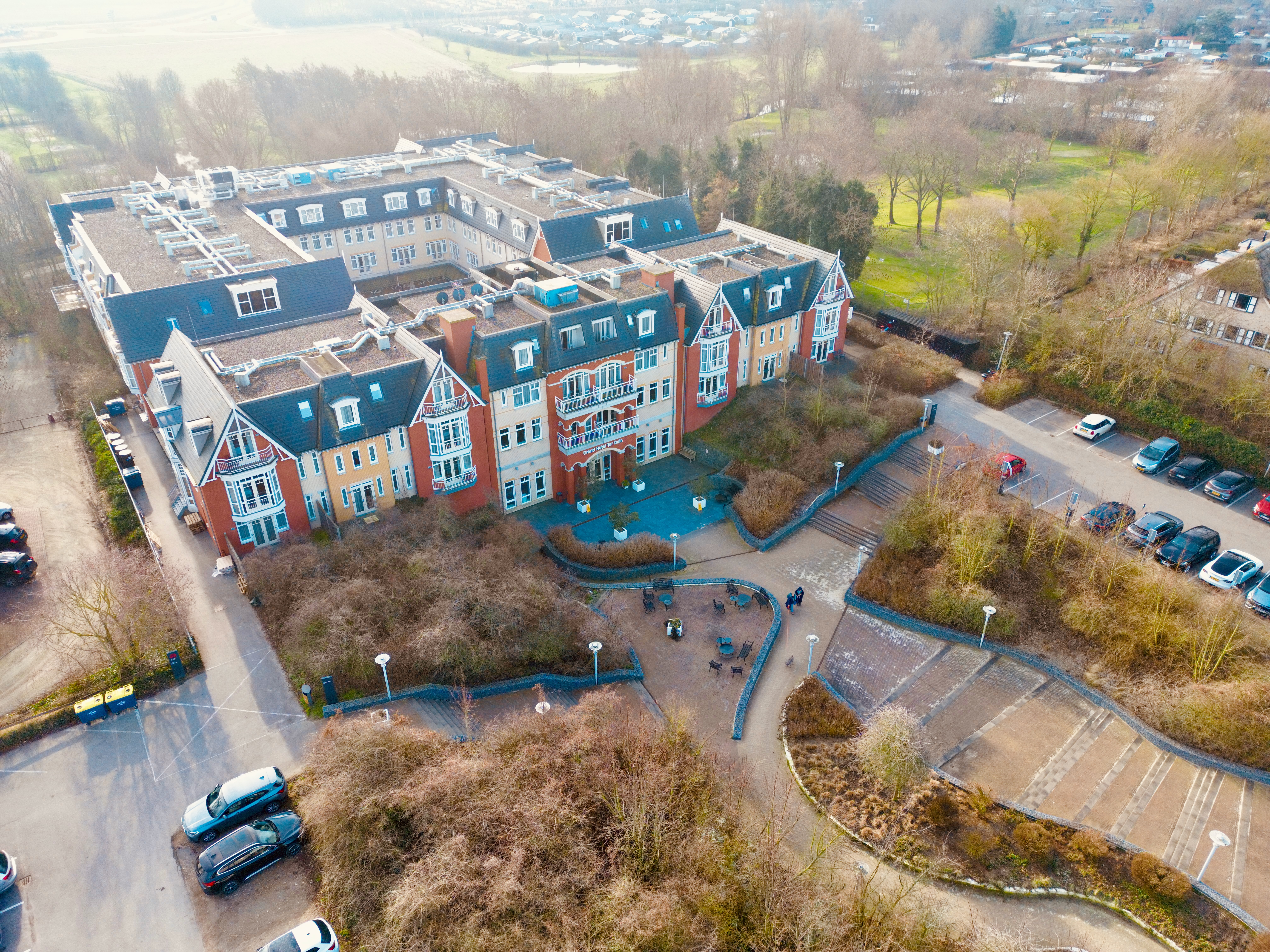 Grand Hotel Ter Duin review aerial perspective of the hotel entrance in Burgh Haamstede with surrounding gardens, stairways, and parking area captured from above