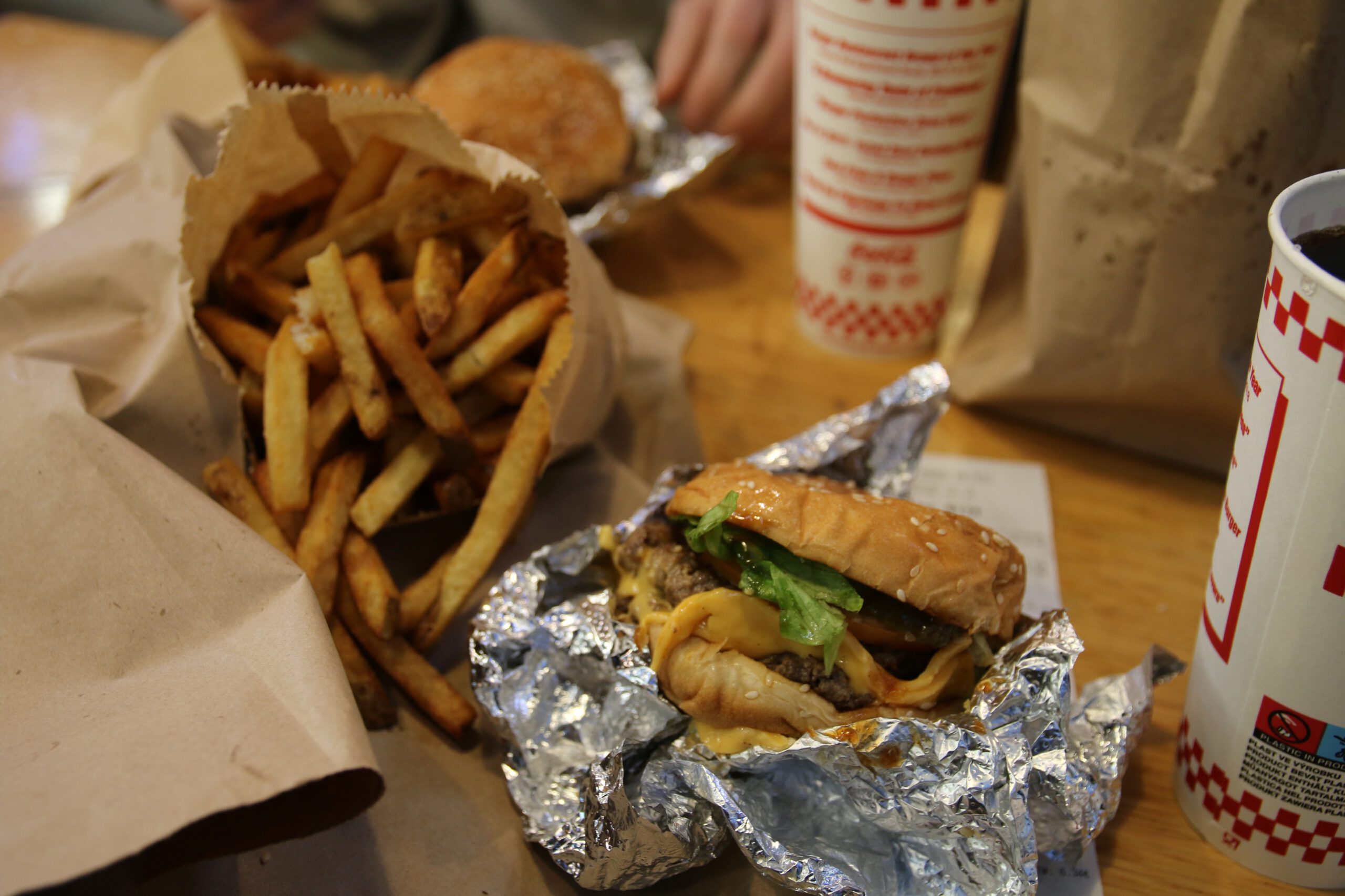 Juicy cheeseburger with melted cheese and fresh lettuce, large portion of fries and refillable soda inside Five Guys Netherlands restaurant in Rotterdam