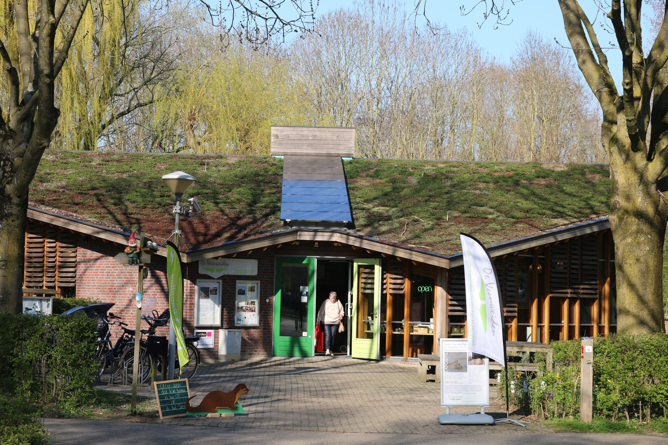 Bezoekerscentrum De Veenweiden in Alphen aan den Rijn with a welcoming entrance, green roof, and peaceful nature setting