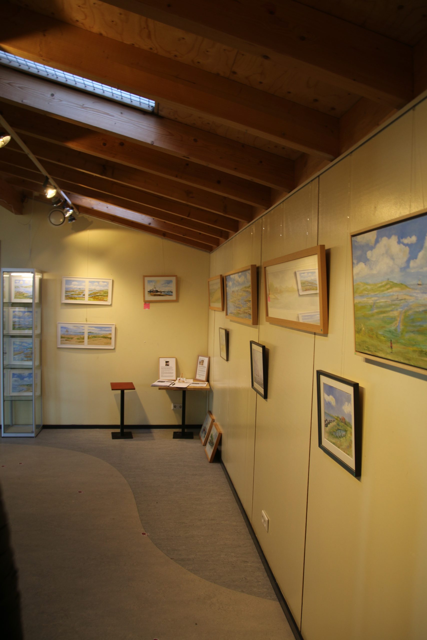 Bezoekerscentrum De Veenweiden art gallery with framed landscape paintings, warm interior design, and a local exhibition space