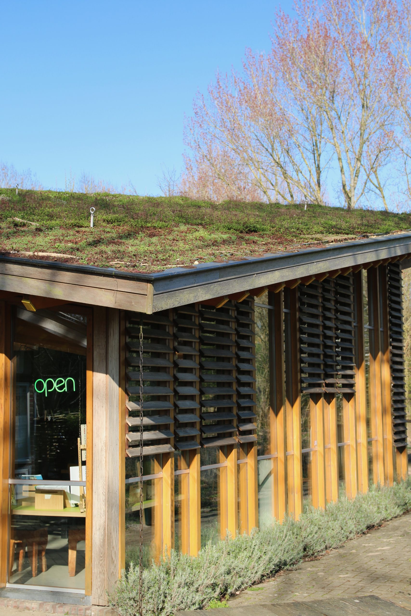 Bezoekerscentrum De Veenweiden exterior with sustainable wooden architecture, green roof, and open entrance in a peaceful natural setting