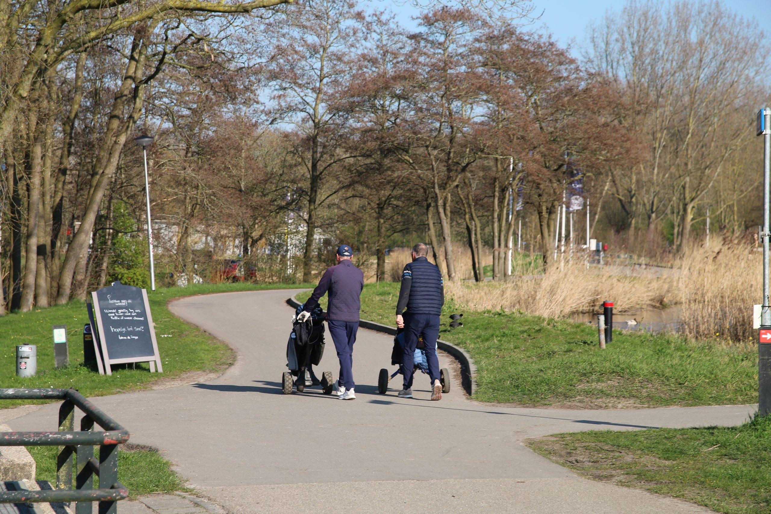 Golfclub Zeegersloot golfers walking with golf trolleys near the course in Alphen aan den Rijn