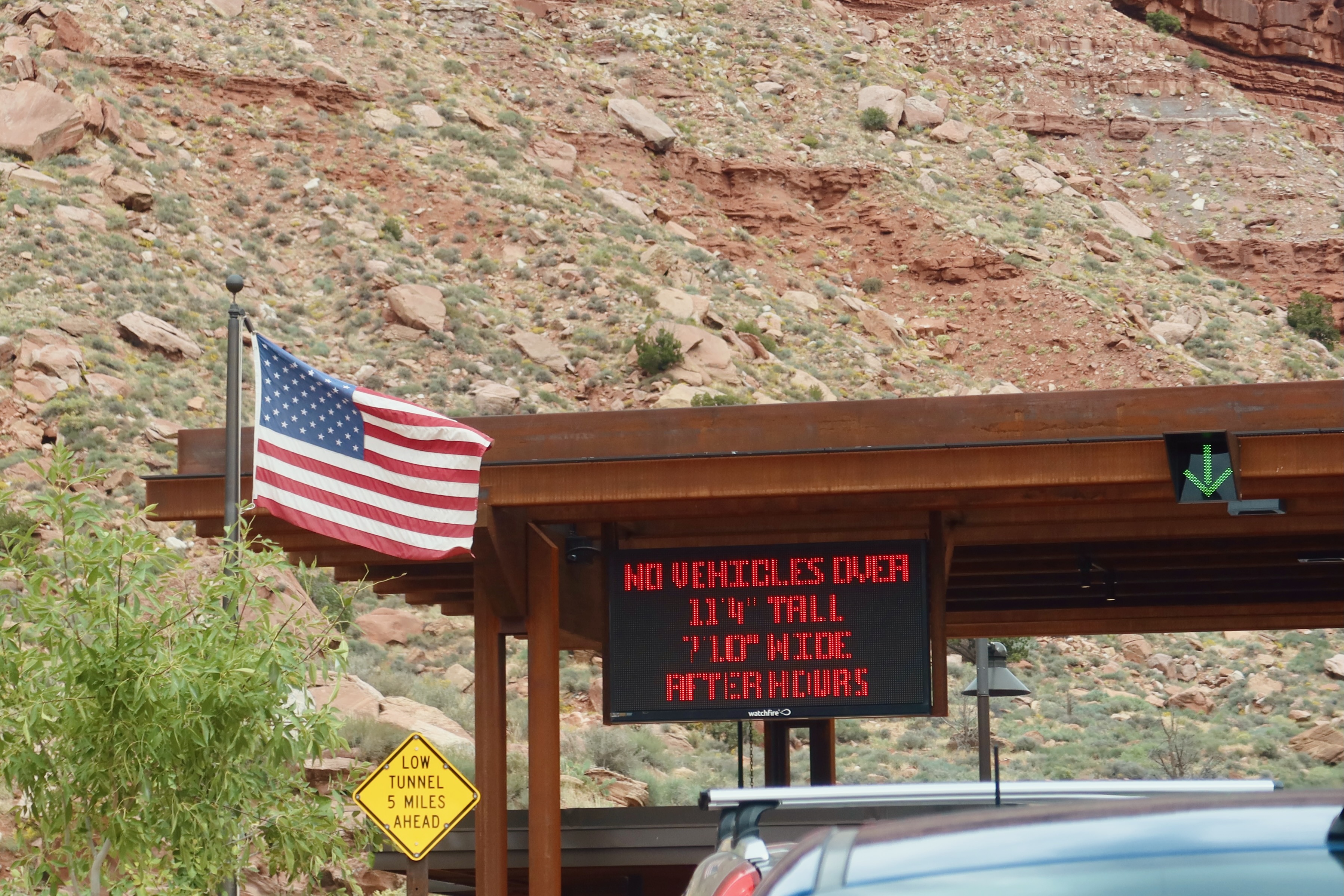 Zion National Park tunnel checkpoint in Utah with American flag, red rock cliffs, and road warning sign in West USA