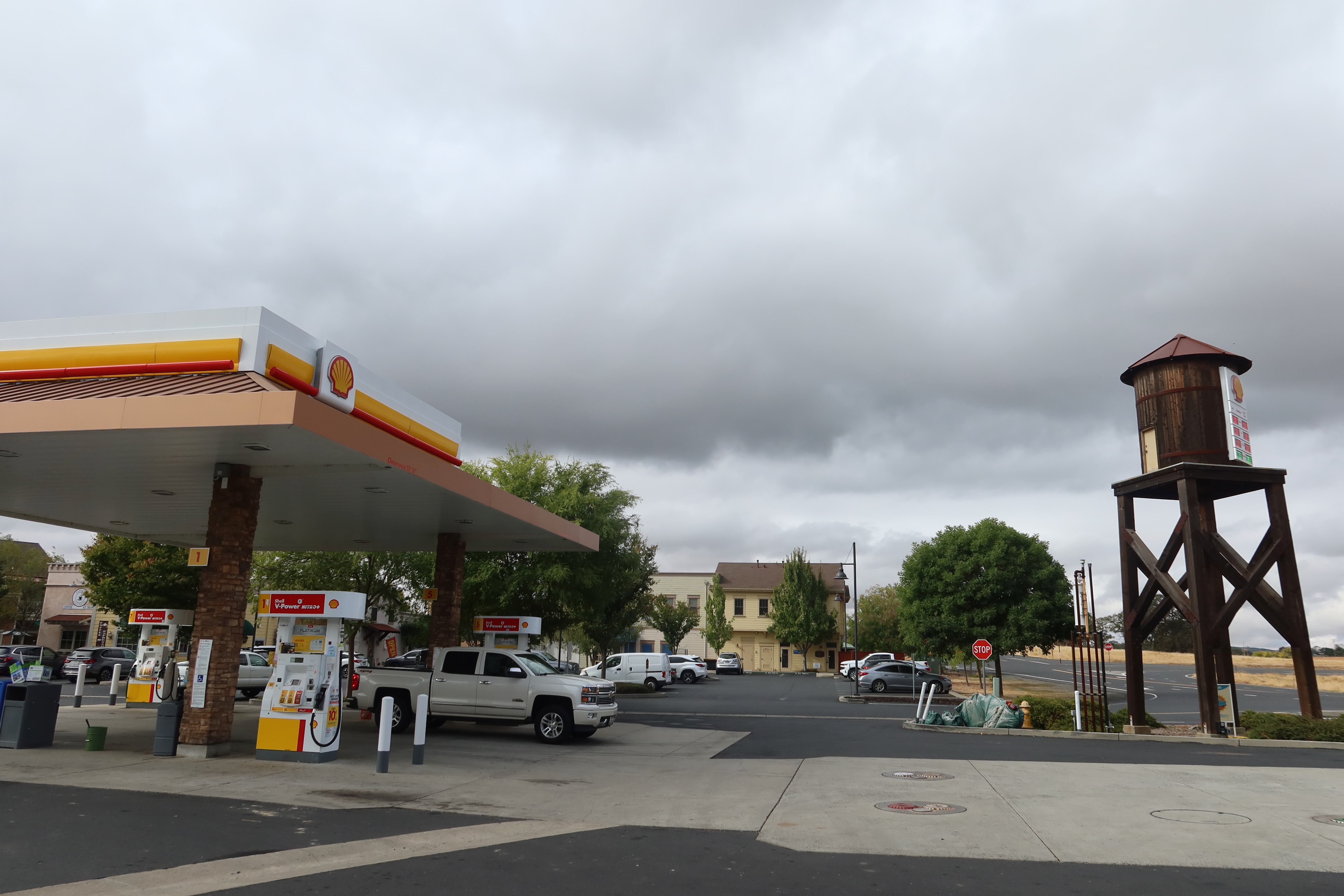 Gas stations in America, Shell station in Copperopolis California with pickup truck, water tower, and dark clouds above a quiet road trip stop