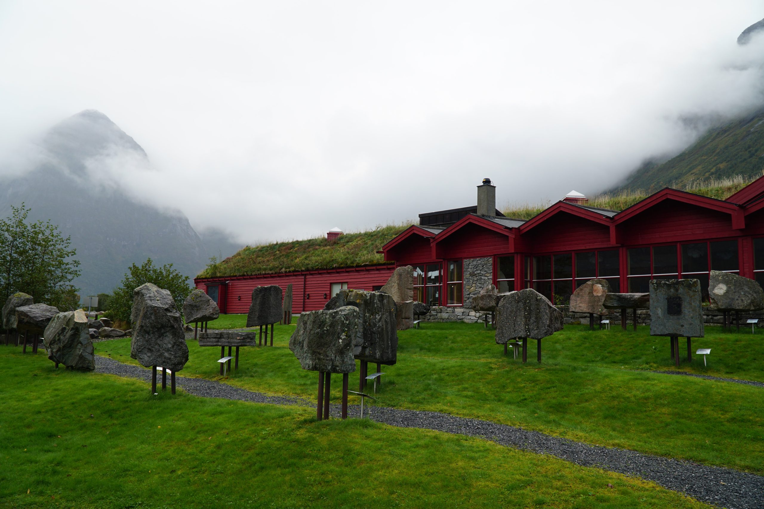 Jostedalsbreen National Park Center red visitor building with geological garden, grass roof and misty Norwegian mountains