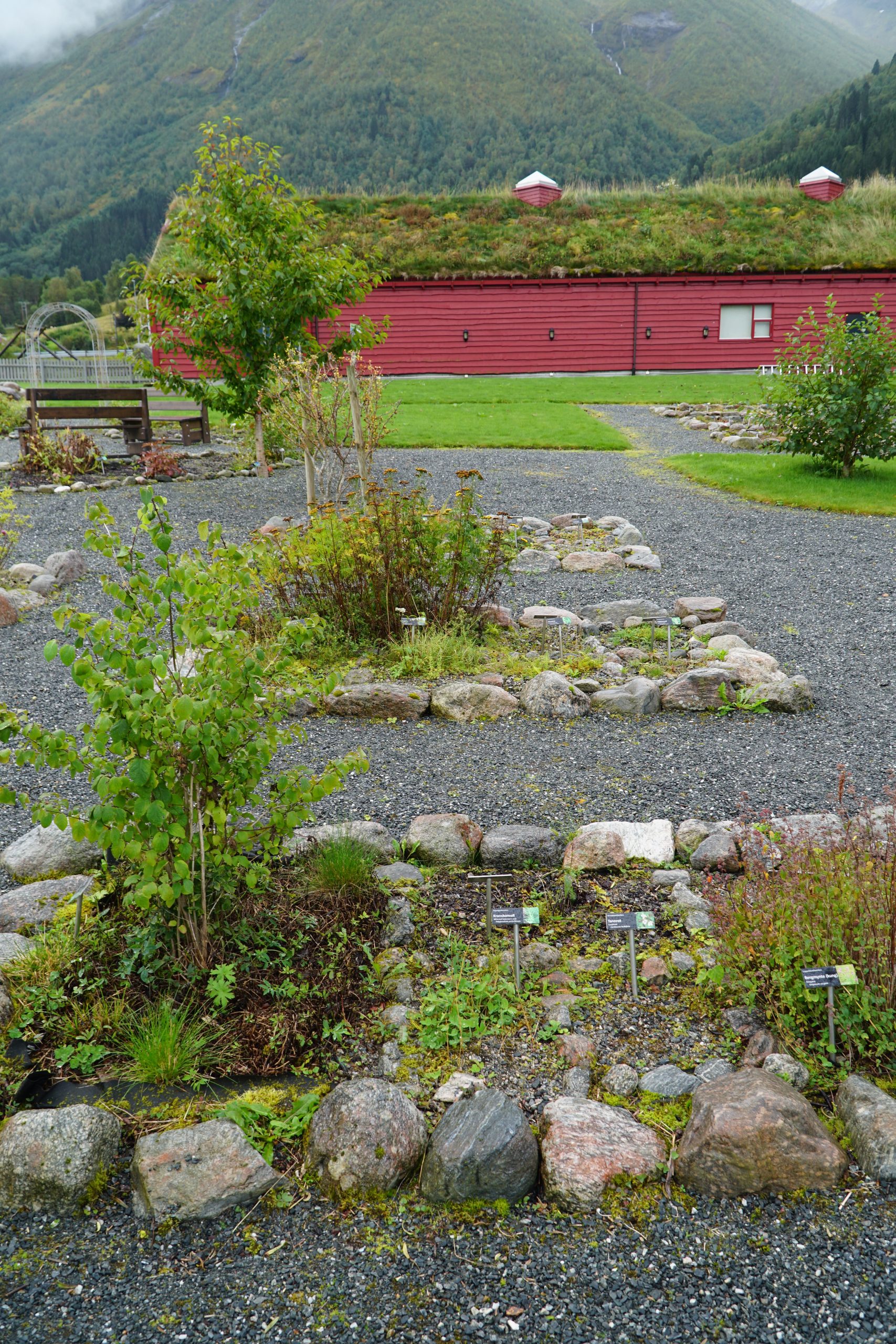 Jostedalsbreen National Park Center fjord and mountain garden with native plants, rocks and red visitor building in Oppstryn Norway