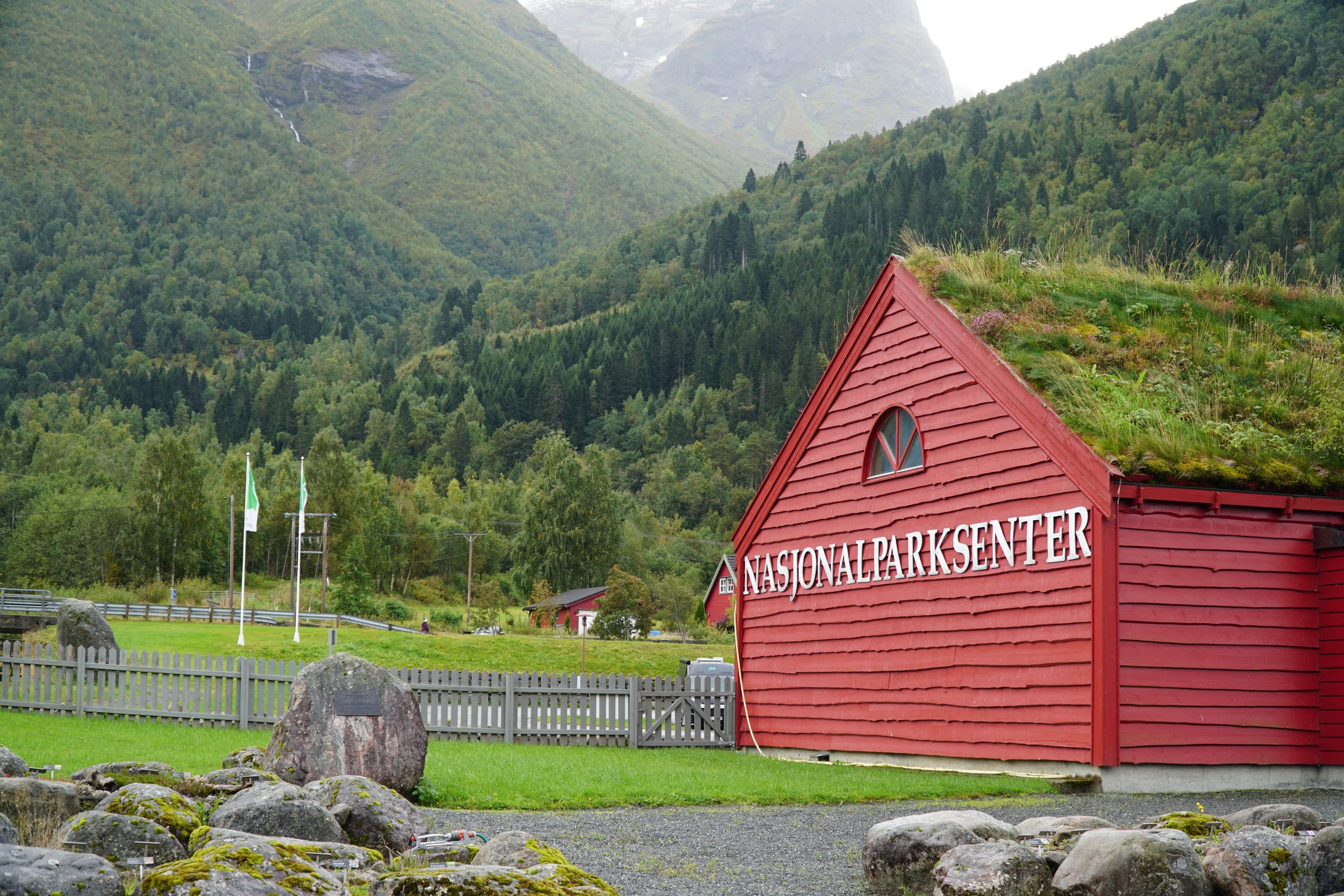 Jostedalsbreen National Park Center entrance building with red wood facade, green roof and mountain scenery in Norway
