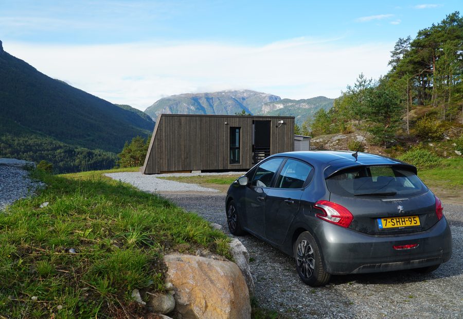Peugeot 208 parked beside a modern cabin during a Sogndal Fjordpanorama Review in Norway, with mountain views and green fjord landscape