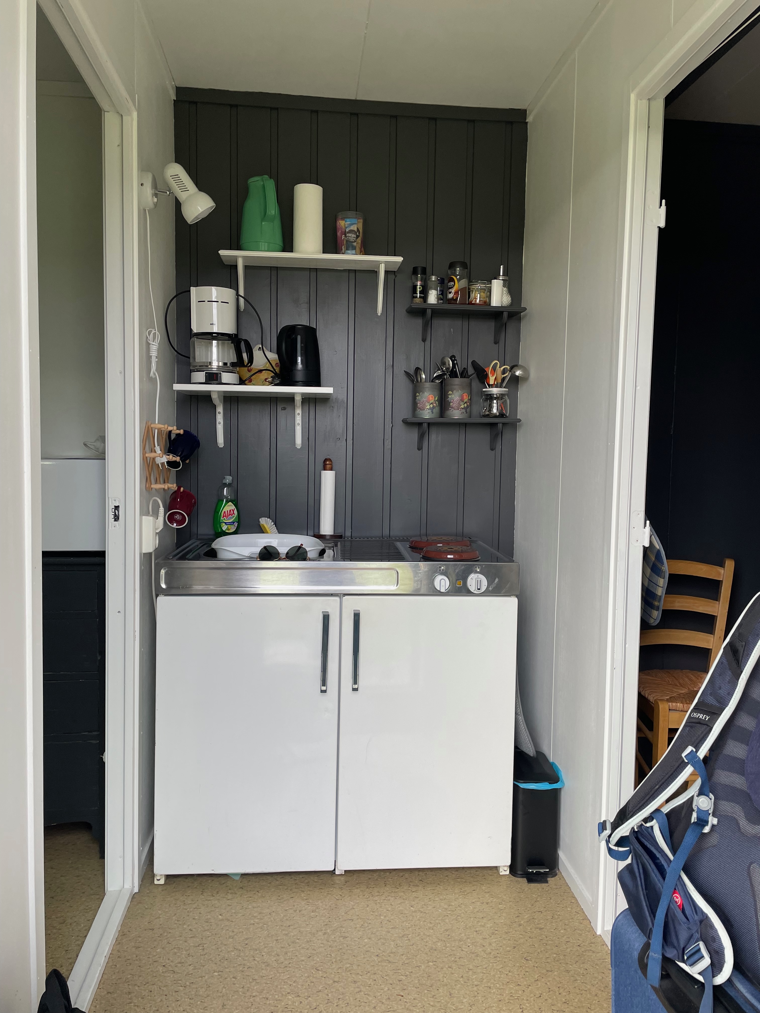 Airbnb in Stjordal Norway, compact kitchenette inside the cabin with a sink, coffee maker, kettle, shelves, basic cooking items, and a view toward the bedroom.