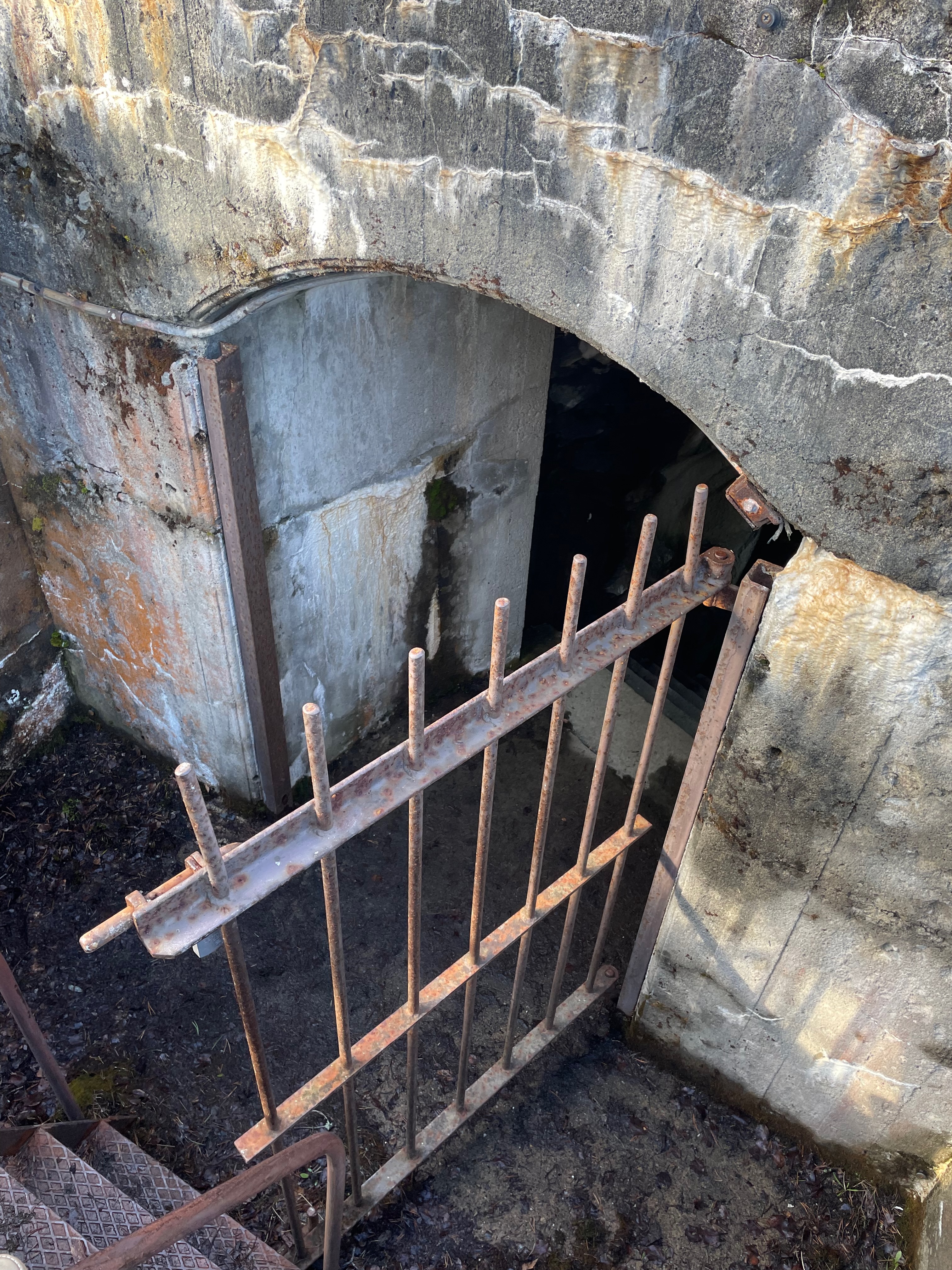 Hegra Fortress underground entrance with old concrete walls, a rusty metal gate, and a dark tunnel leading into the historic fort in Norway