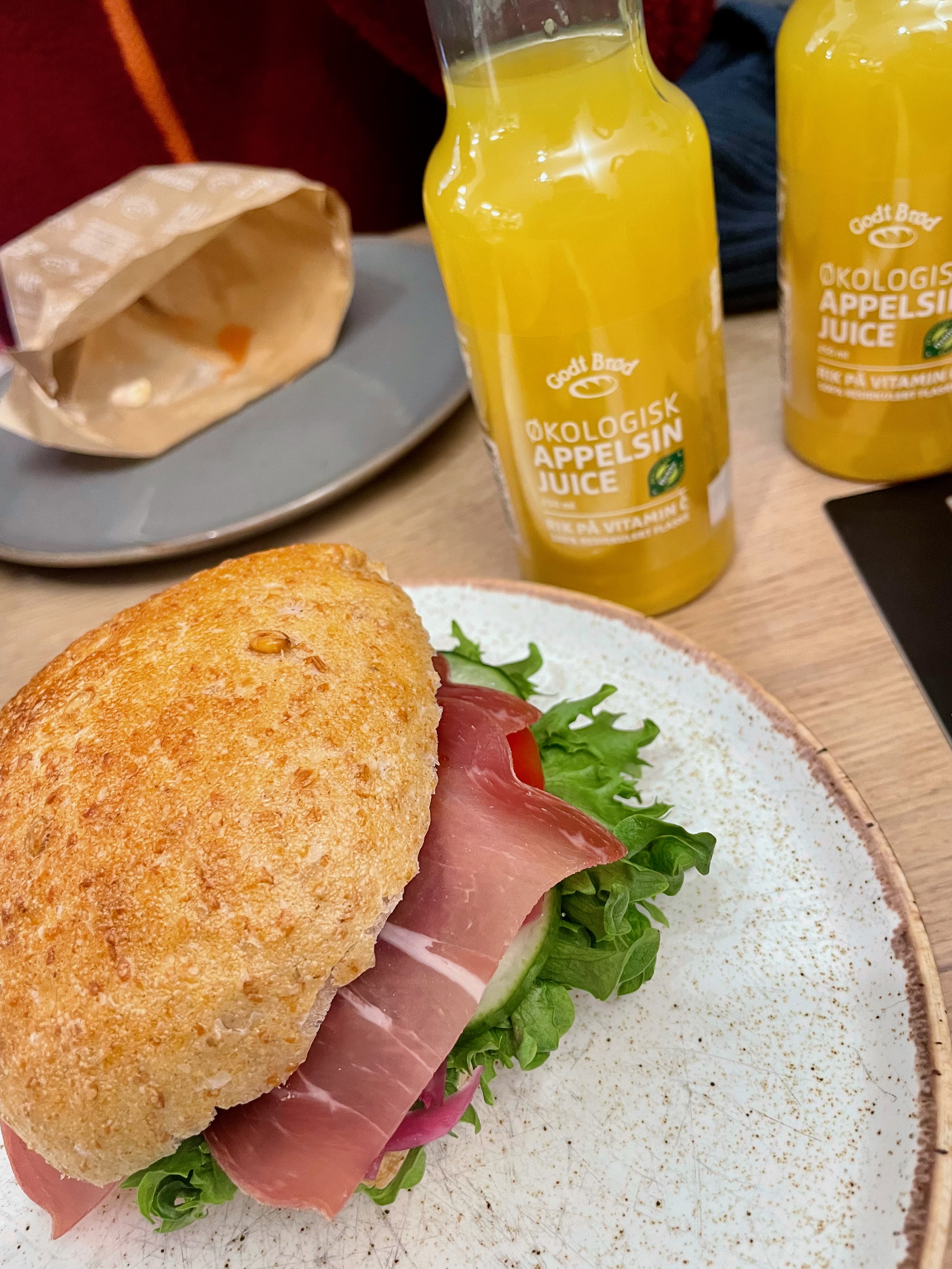 Godt Brød Trondheim lunch with a fresh filled sandwich and organic apple orange juice on the table