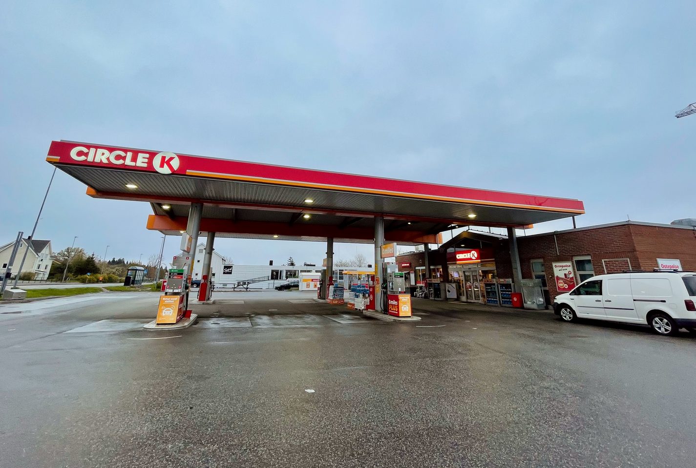 Circle K Molde gas station on a rainy day with fuel pumps, shop entrance, wet pavement, and a cloudy Norwegian sky
