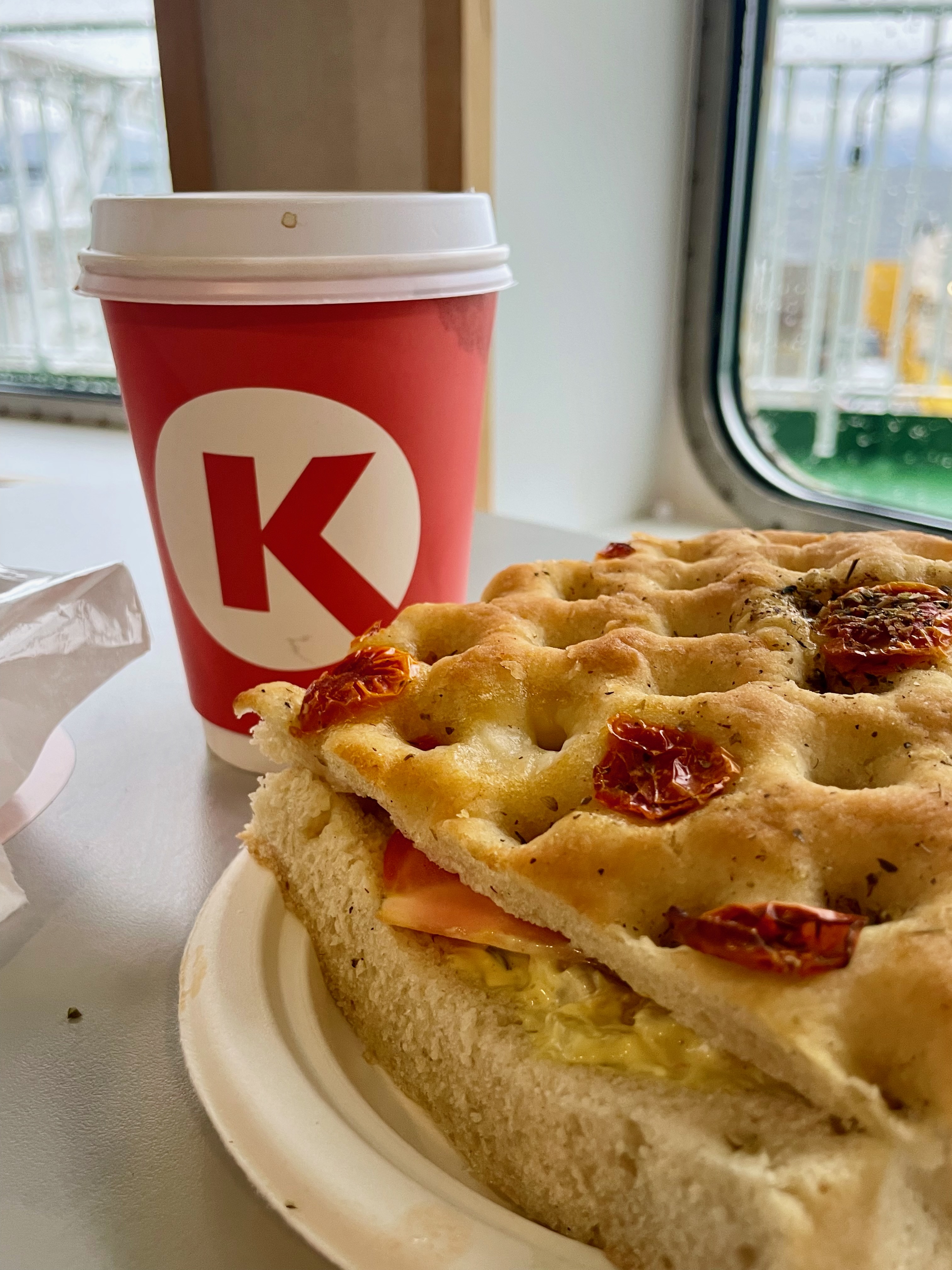 Circle K Molde coffee and chicken focaccia sandwich on a ferry table by the window during a Norway road trip