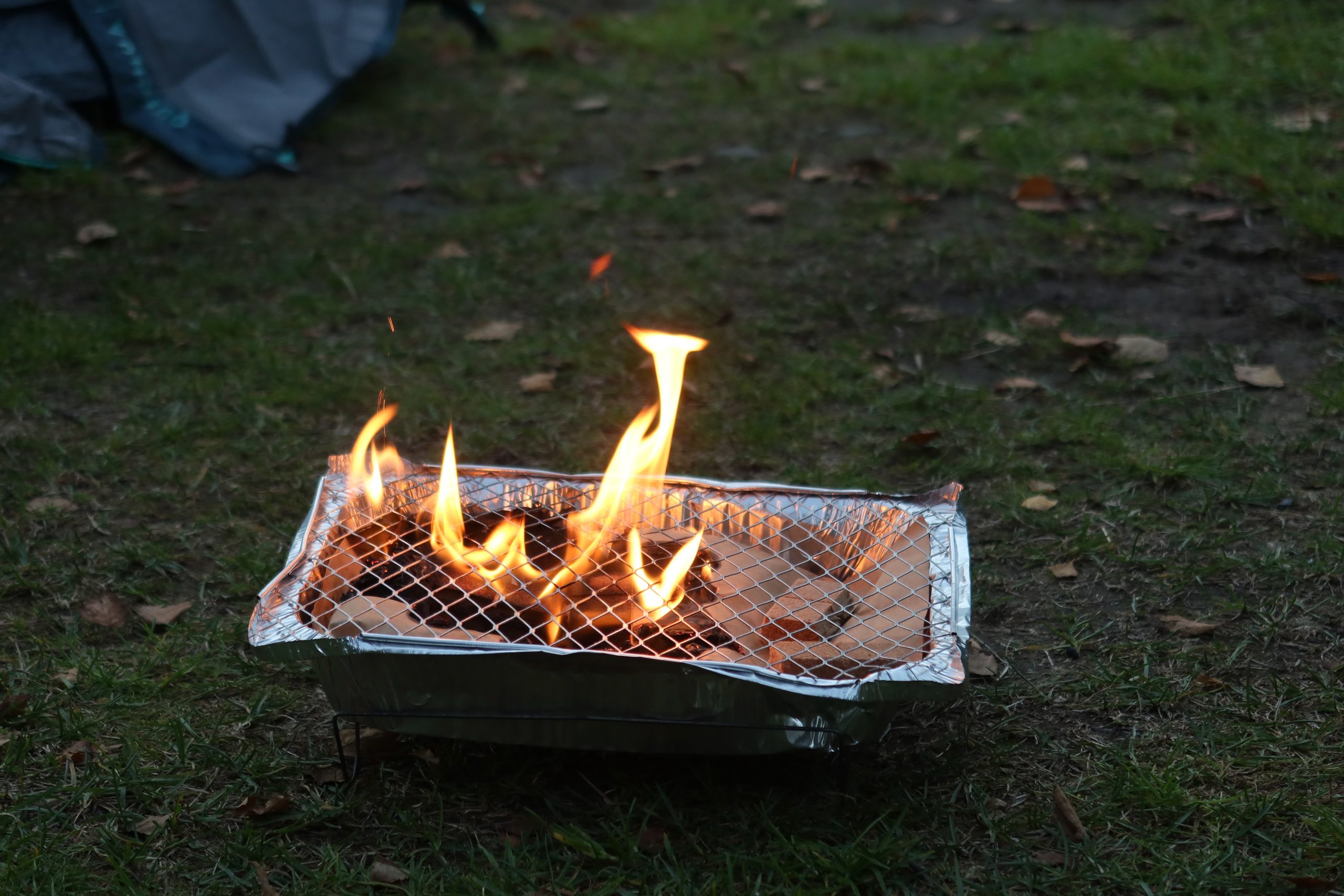Disposable barbecue with burgers and meat cooking at Seim Camping Røldal during a simple camping dinner in Norway.