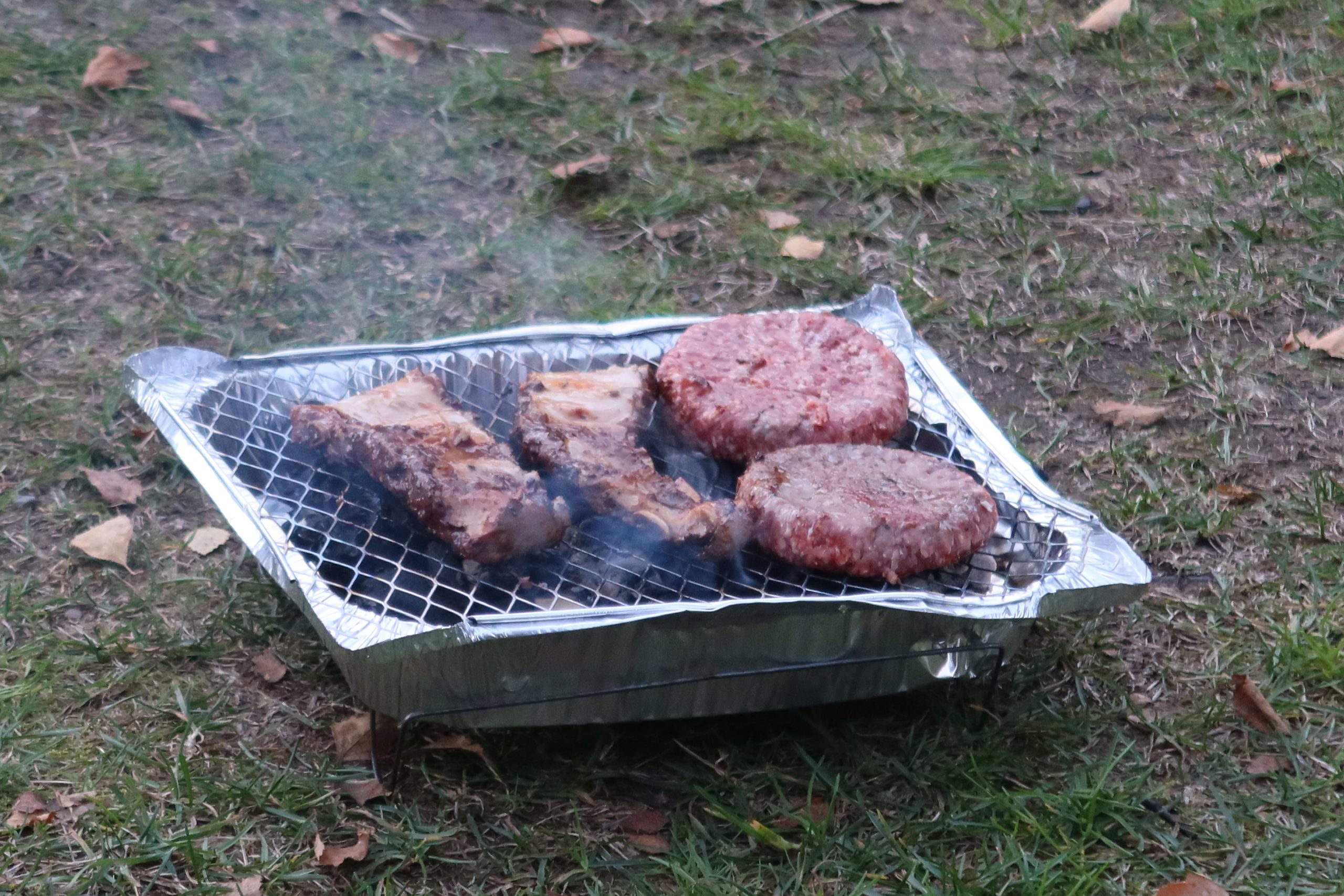 Disposable barbecue with open flames at Seim Camping Røldal, used for a simple evening meal while camping in Norway.