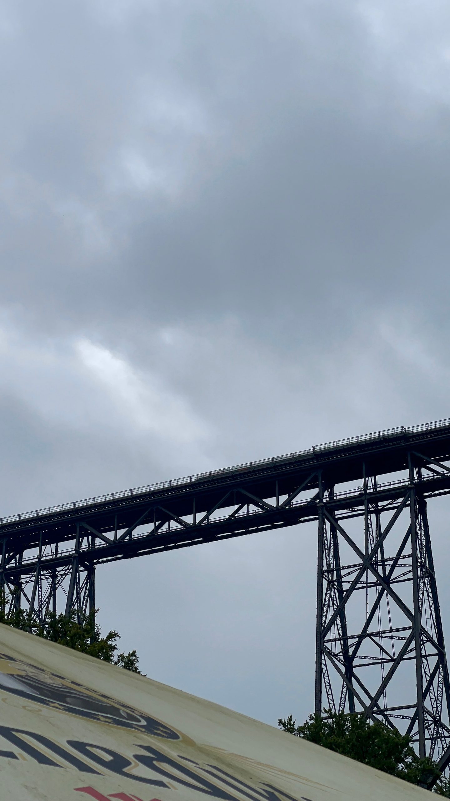 Müngstener Brücke steel railway structure seen from below in Solingen, Germany, with cloudy skies above the historic bridge, a train is crossing over the bridge