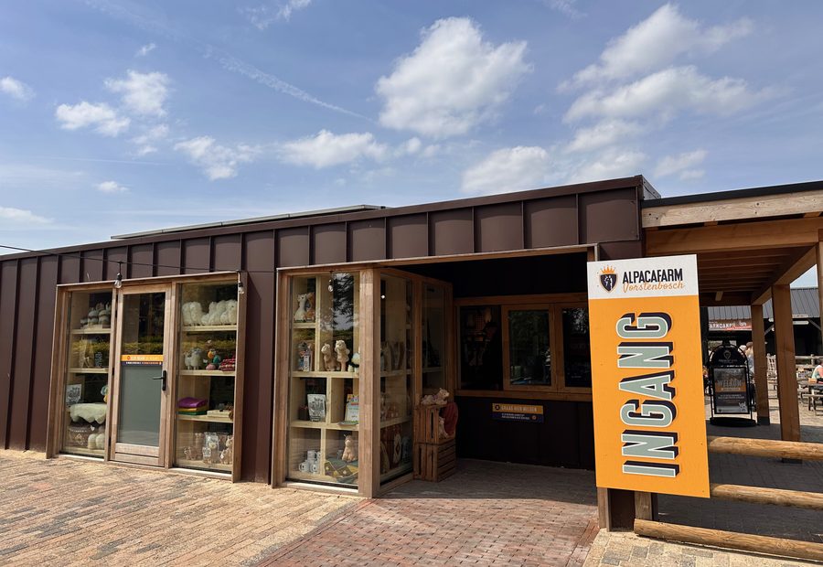 Alpacafarm Vorstenbosch review, entrance building with alpaca boutique, large orange welcome sign, and terrace area in North Brabant