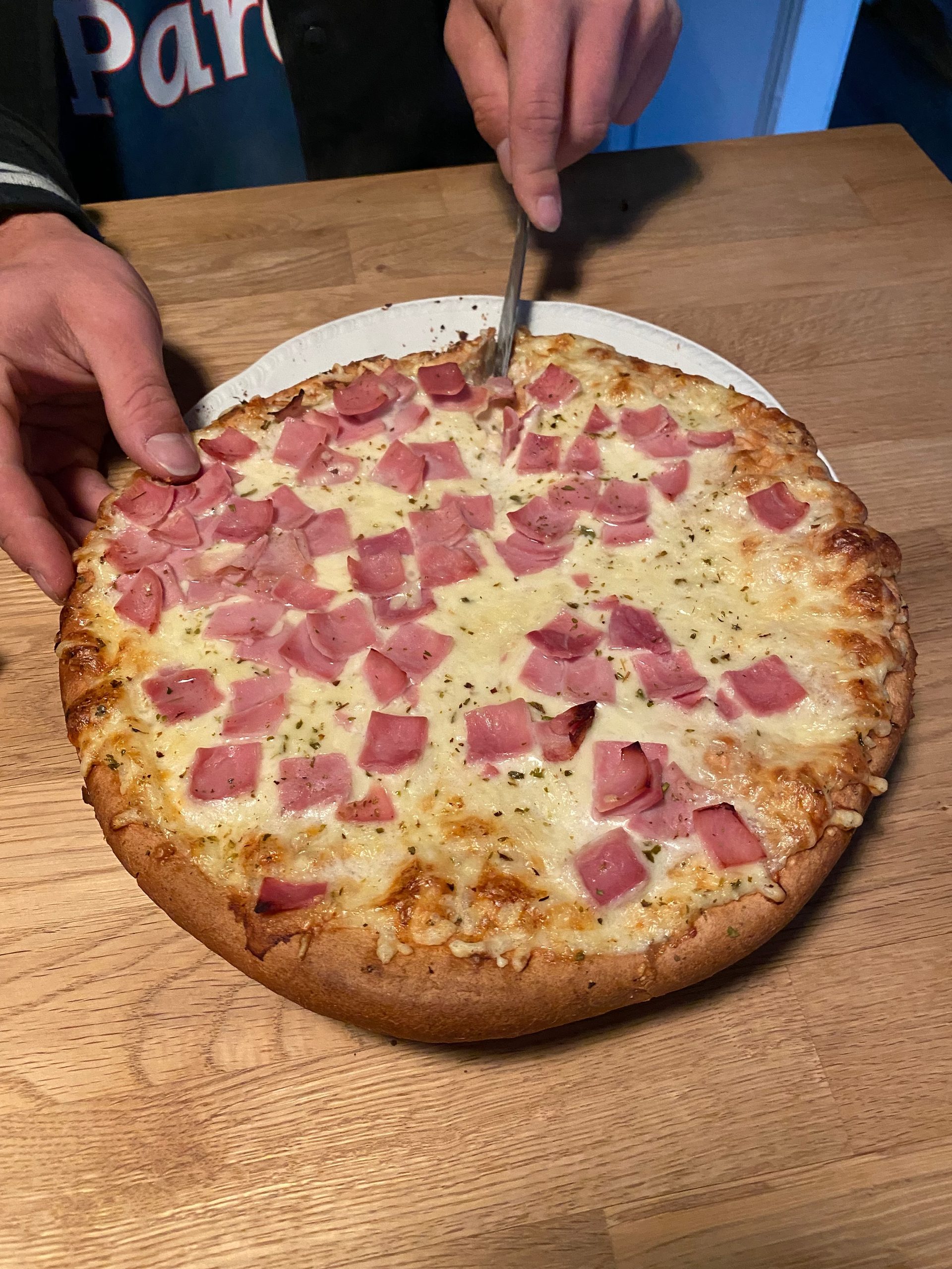 Geiranger Airbnb dinner with homemade ham and cheese pizza on a wooden table inside the fjord view apartment