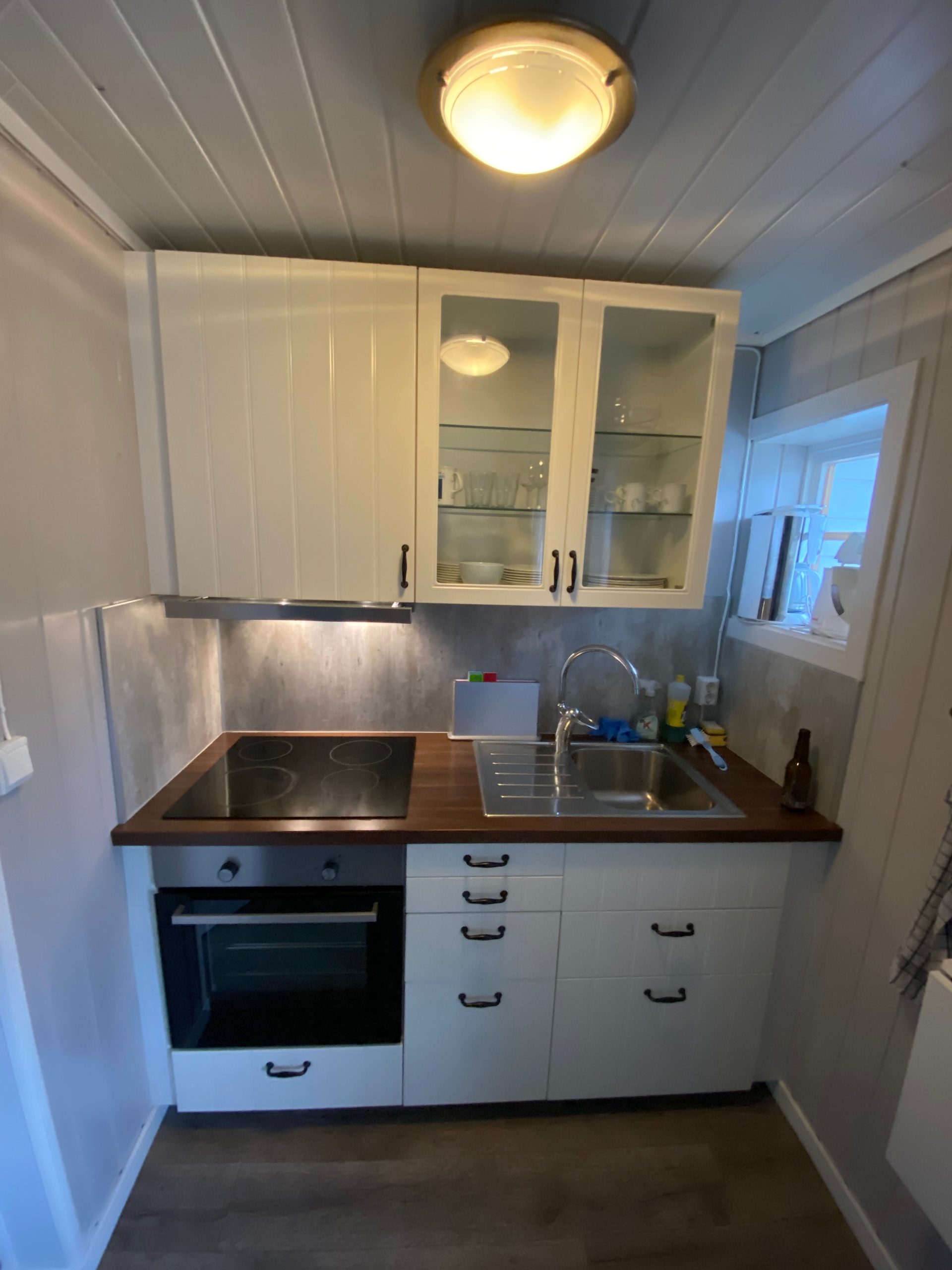 Geiranger Airbnb kitchen with oven, stovetop, sink, white cabinets, and small cooking area inside the fjord view apartment