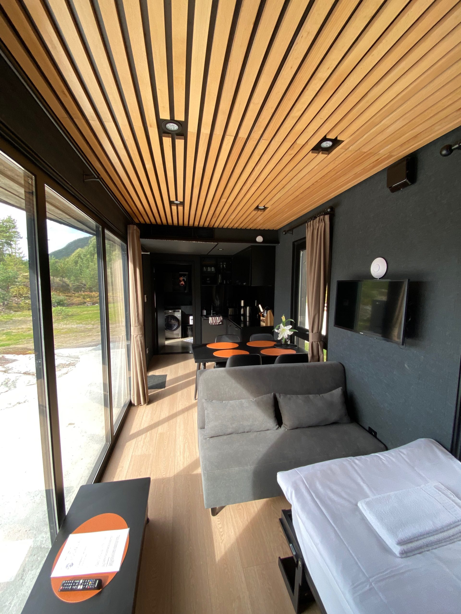 Living area inside Sogndal Fjordpanorama cabin during a Sogndal Fjordpanorama Review, with sofa bed, dining space, TV, and wooden ceiling
