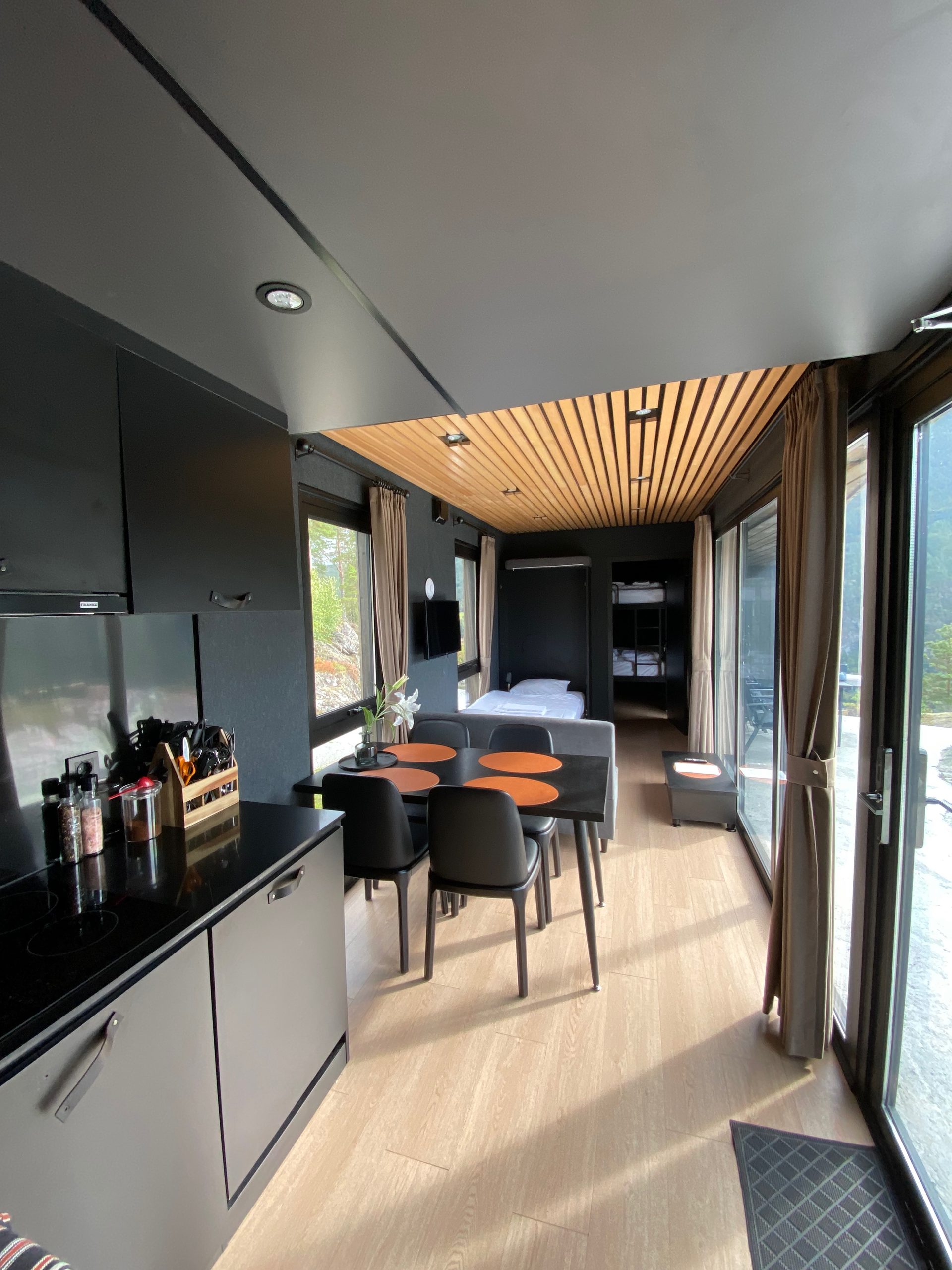 Modern cabin interior at Sogndal Fjordpanorama during a Sogndal Fjordpanorama Review, with kitchen, dining table, fold out bed, and large windows