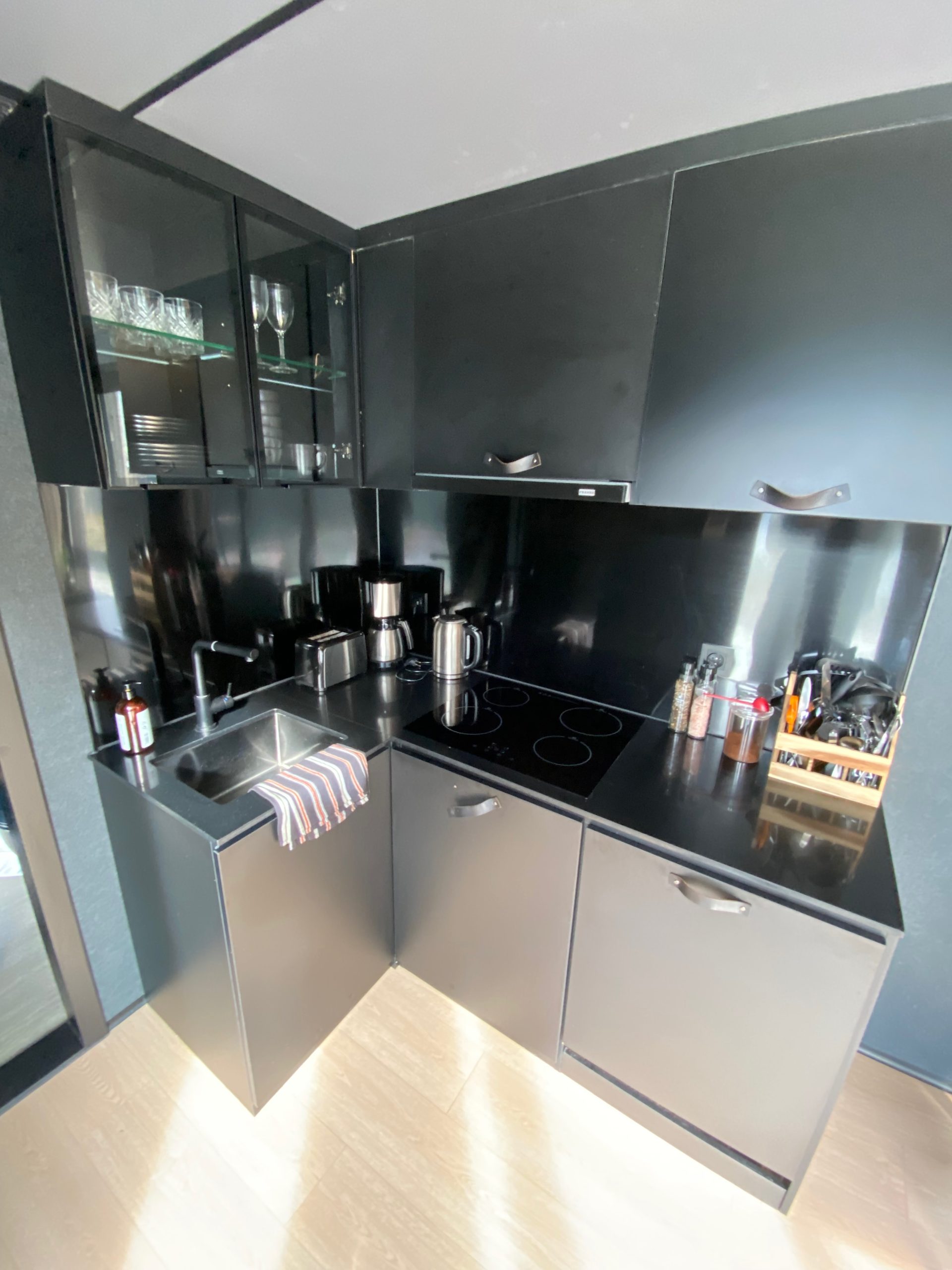 Modern black kitchen inside the cabin during a Sogndal Fjordpanorama Review in Norway, with induction cooktop, sink, coffee maker, and cooking equipment