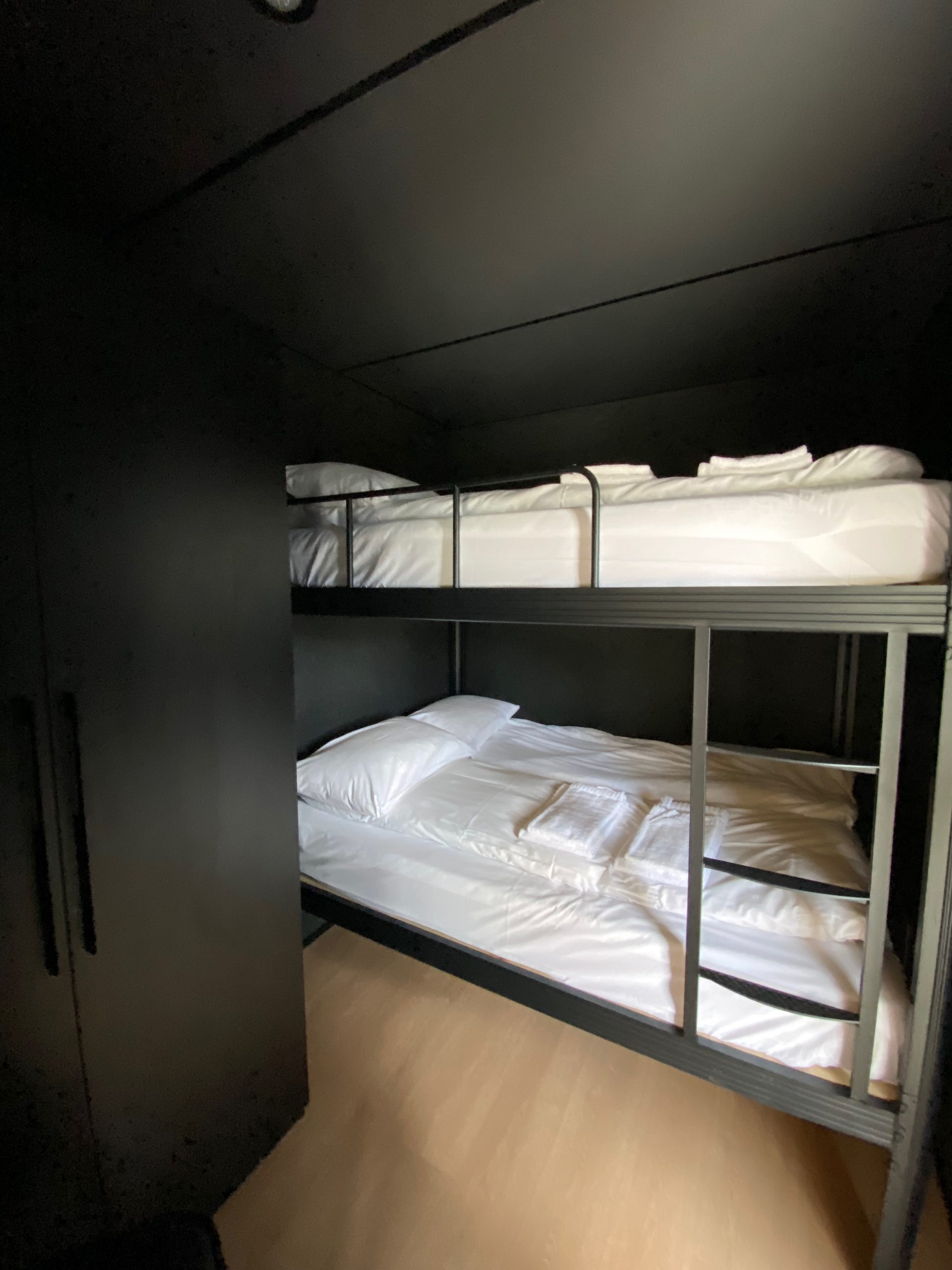 Double bunk bed inside Sogndal Fjordpanorama cabin during a Sogndal Fjordpanorama Review, with white bedding and dark modern walls