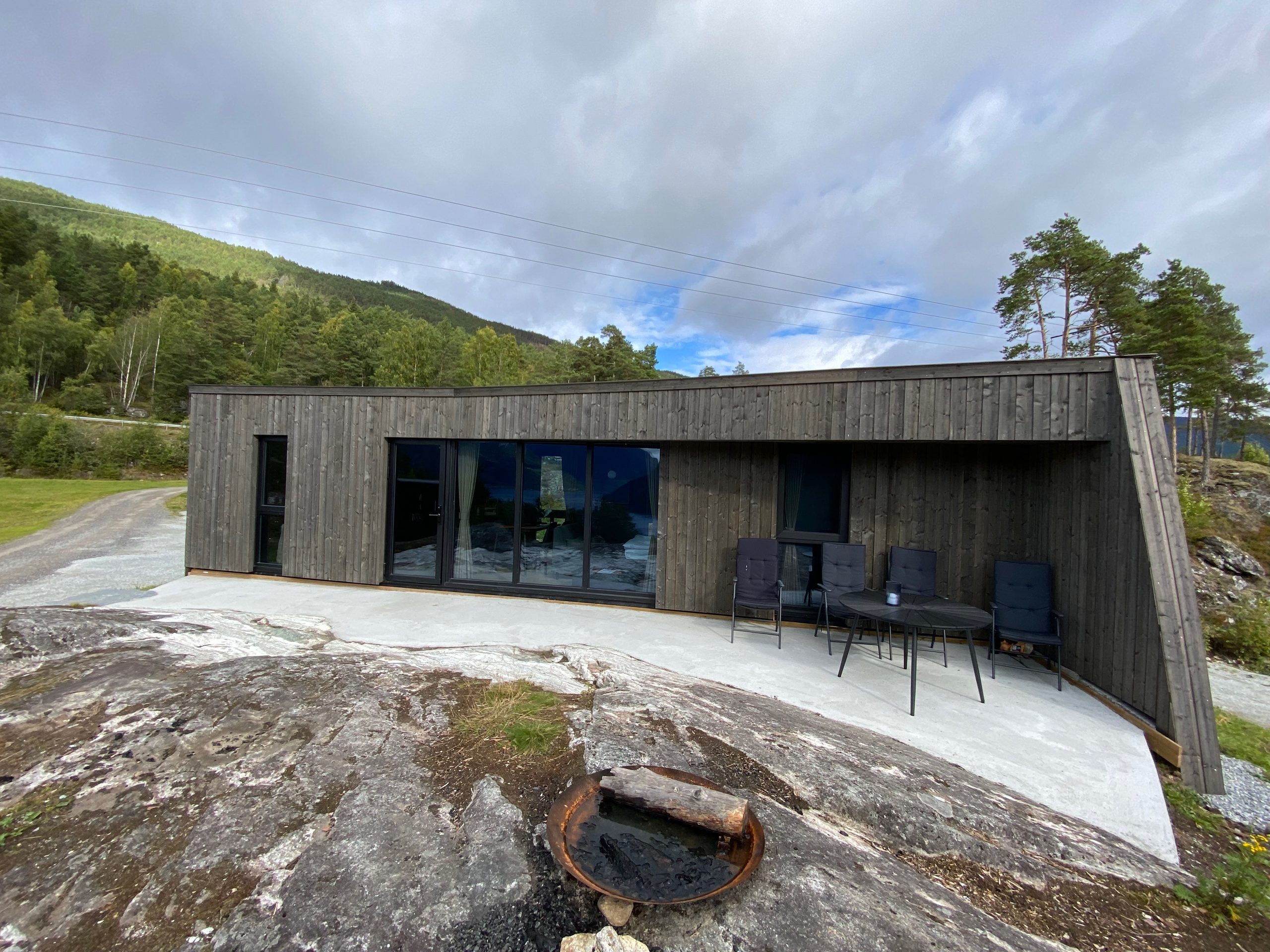 Modern wooden cabin at Sogndal Fjordpanorama in Norway with outdoor seating, rocky landscape, and mountain views during a Sogndal Fjordpanorama Review