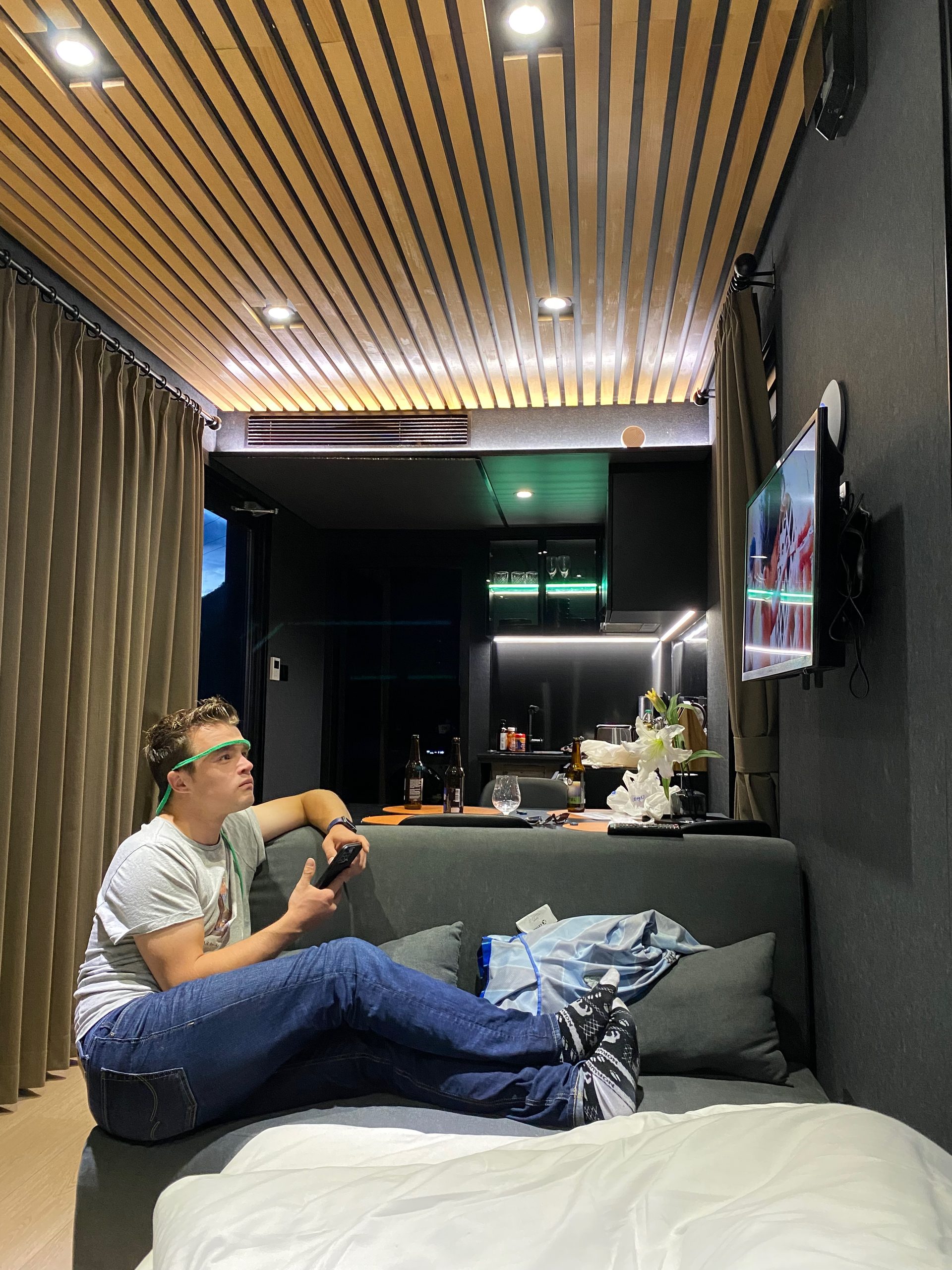 Peter Smit watching TV from the sofa bed inside the cabin during a Sogndal Fjordpanorama Review in Norway