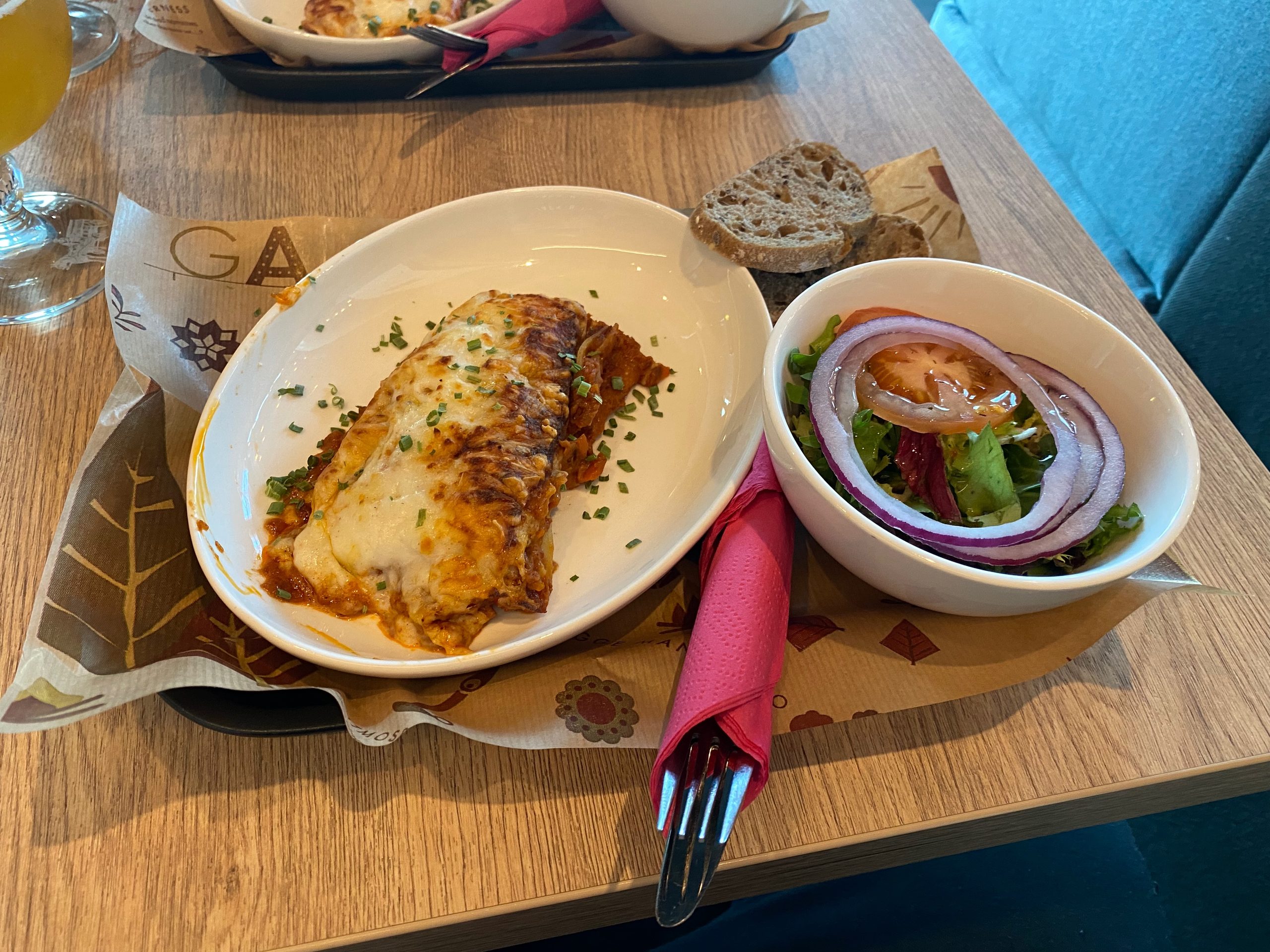 Moxy Hotel Bergen bar meal with lasagna, side salad, and bread during a relaxed hotel dinner in Bergen