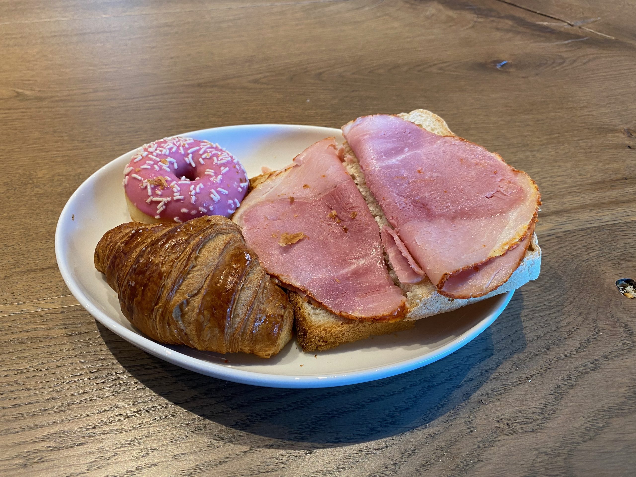 Moxy Hotel Bergen breakfast plate with croissant, ham sandwich, and pink donut during a hotel stay in Bergen