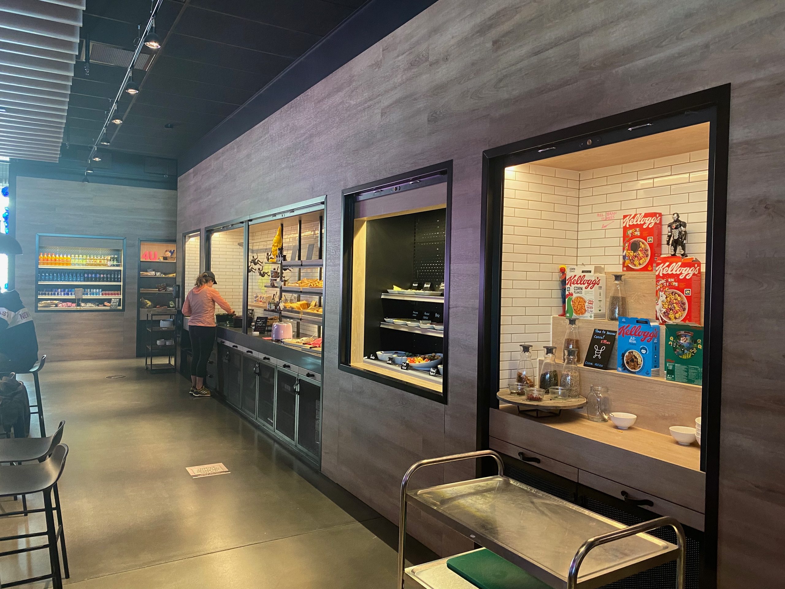 Moxy Hotel Bergen breakfast buffet with cereal, bread, drinks, and a modern industrial dining area in Bergen, Norway