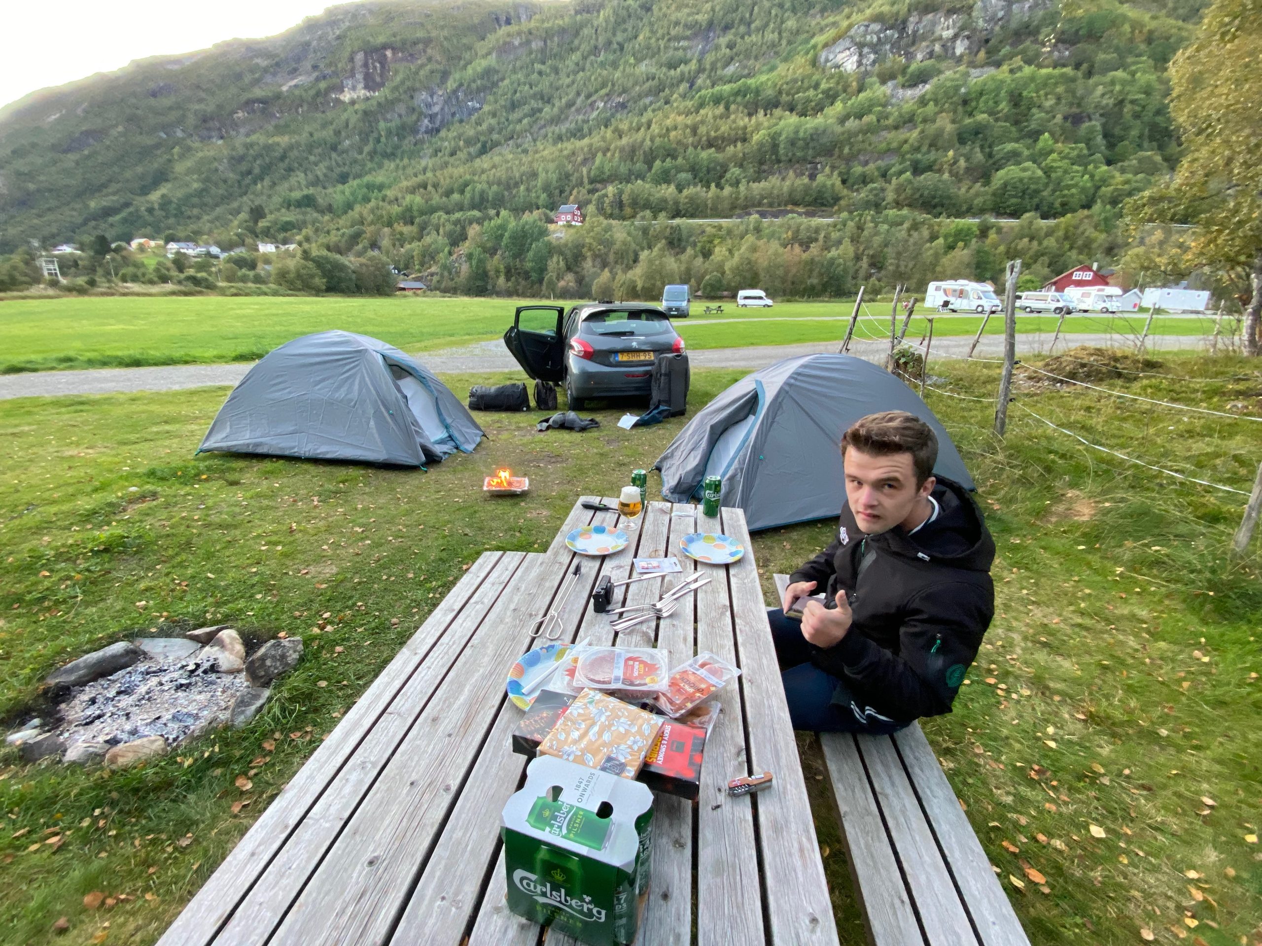 Peter Smit during a simple barbecue dinner at Seim Camping Røldal, sitting at a picnic table between two tents in the mountains of Norway.