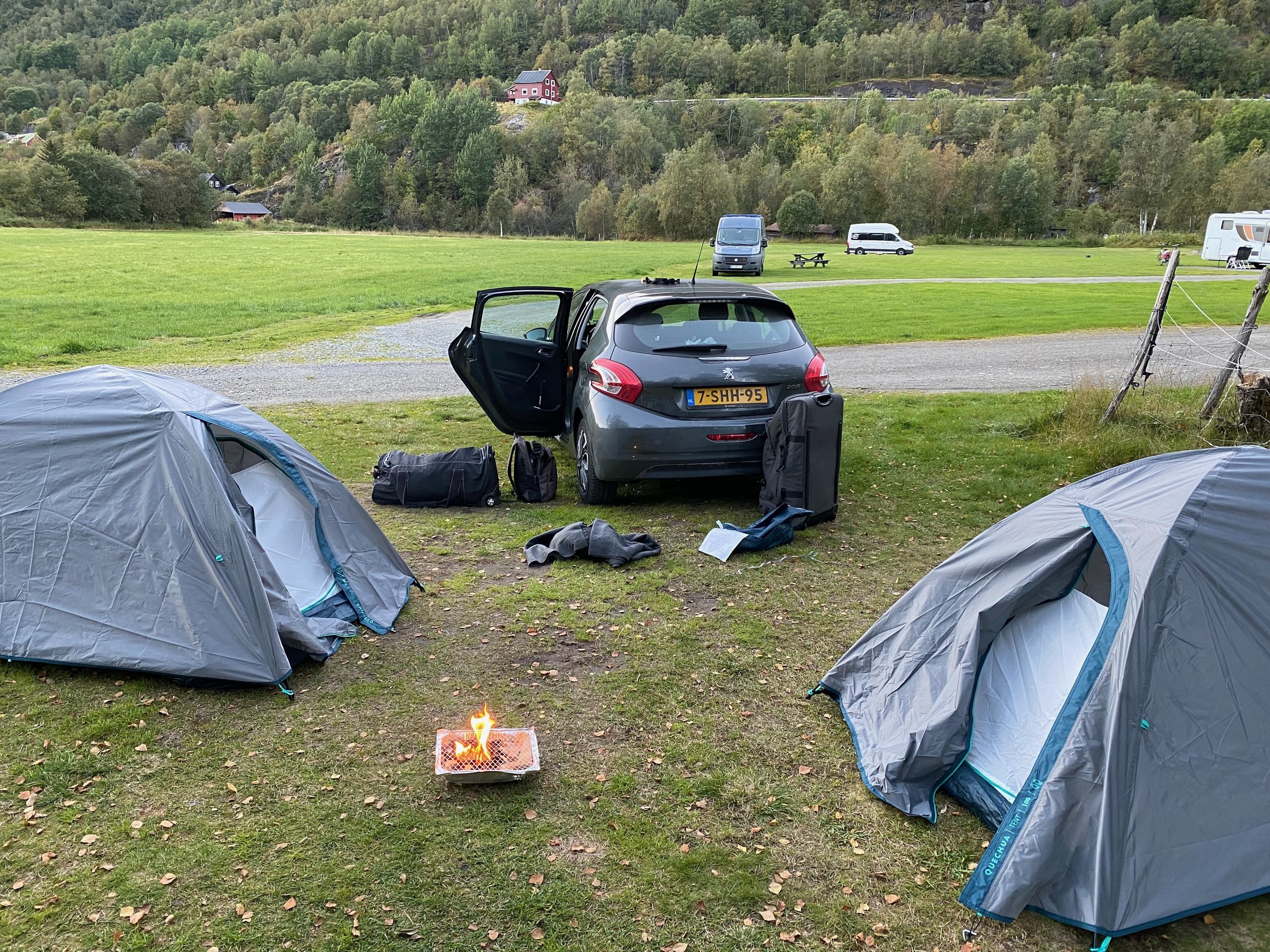 Camping setup at Seim Camping Røldal with two Decathlon tents, a Peugeot 208, a disposable barbecue, and mountain views in Norway.