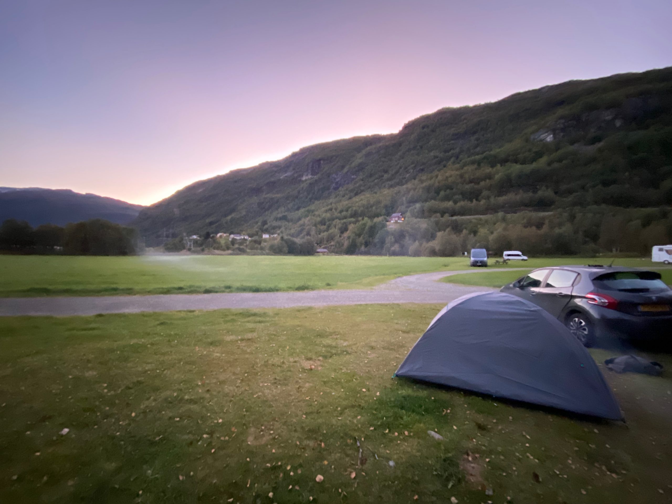 Quiet evening view from Seim Camping Røldal, with a Decathlon tent beside the car and soft sunset light over the Norwegian mountains.