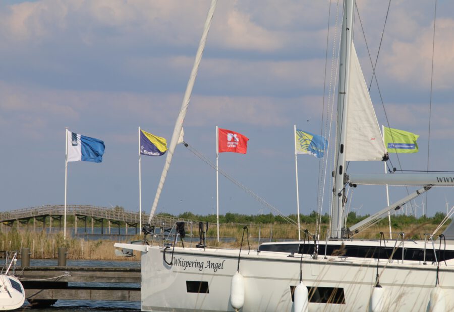 Marker Wadden island visit with a sailboat in the harbor and visible flags from Boskalis, Postcode Loterij, Natuurmonumenten and Marker Wadden