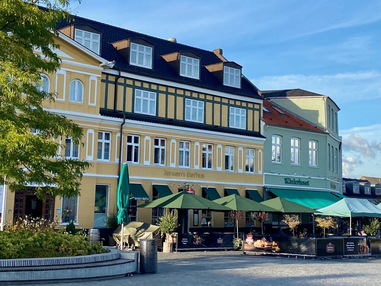 Jensens Bofhus Silkeborg review showing the exterior of the former restaurant at Torvet 5 in Silkeborg Denmark with outdoor seating green umbrellas and Hotel Dania in the background