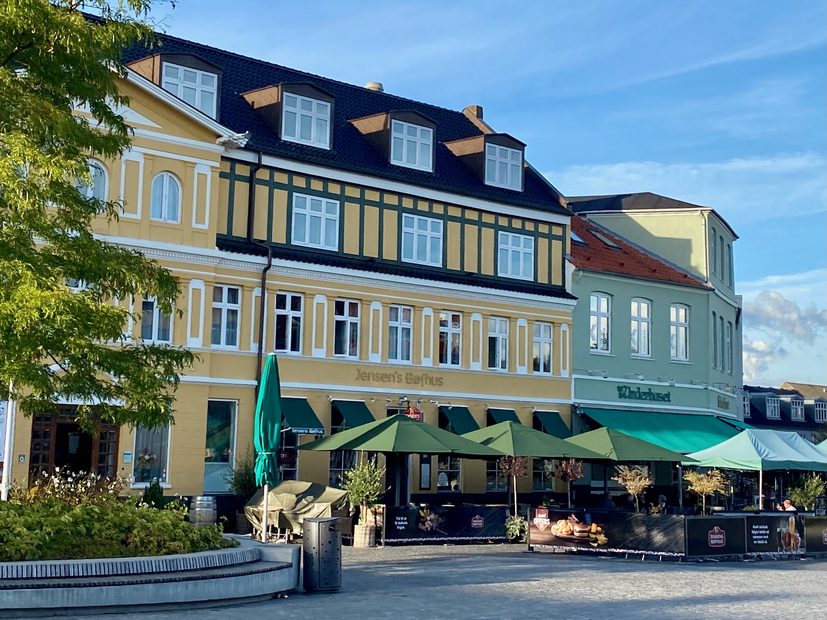 Jensens Bofhus Silkeborg review showing the exterior of the former restaurant at Torvet 5 in Silkeborg Denmark with outdoor seating green umbrellas and Hotel Dania in the background
