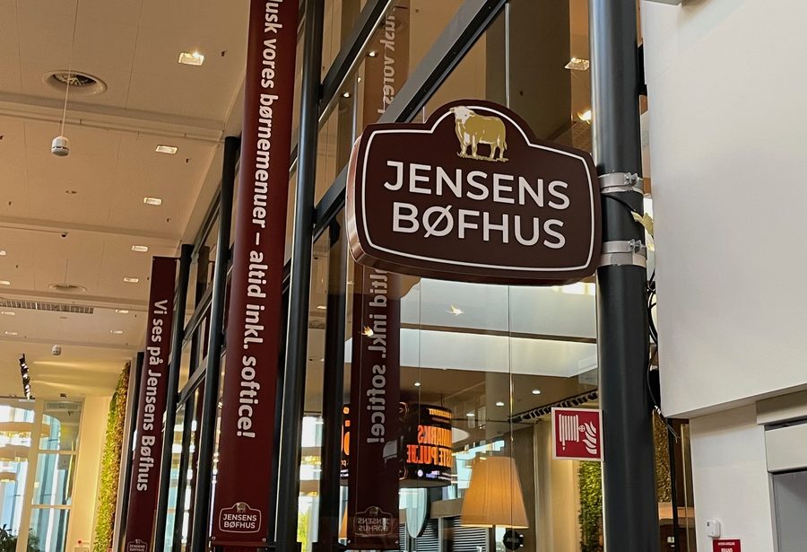 Jensens Bøfhus Kolding review restaurant sign inside Kolding Storcenter, showing the brown Jensens Bøfhus logo sign with cow illustration and red Danish buffet banners